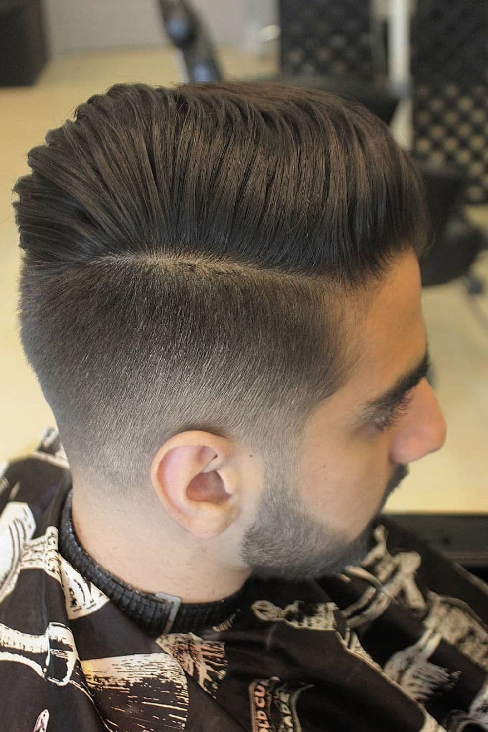 A man with a comb over fade with a hard side part.