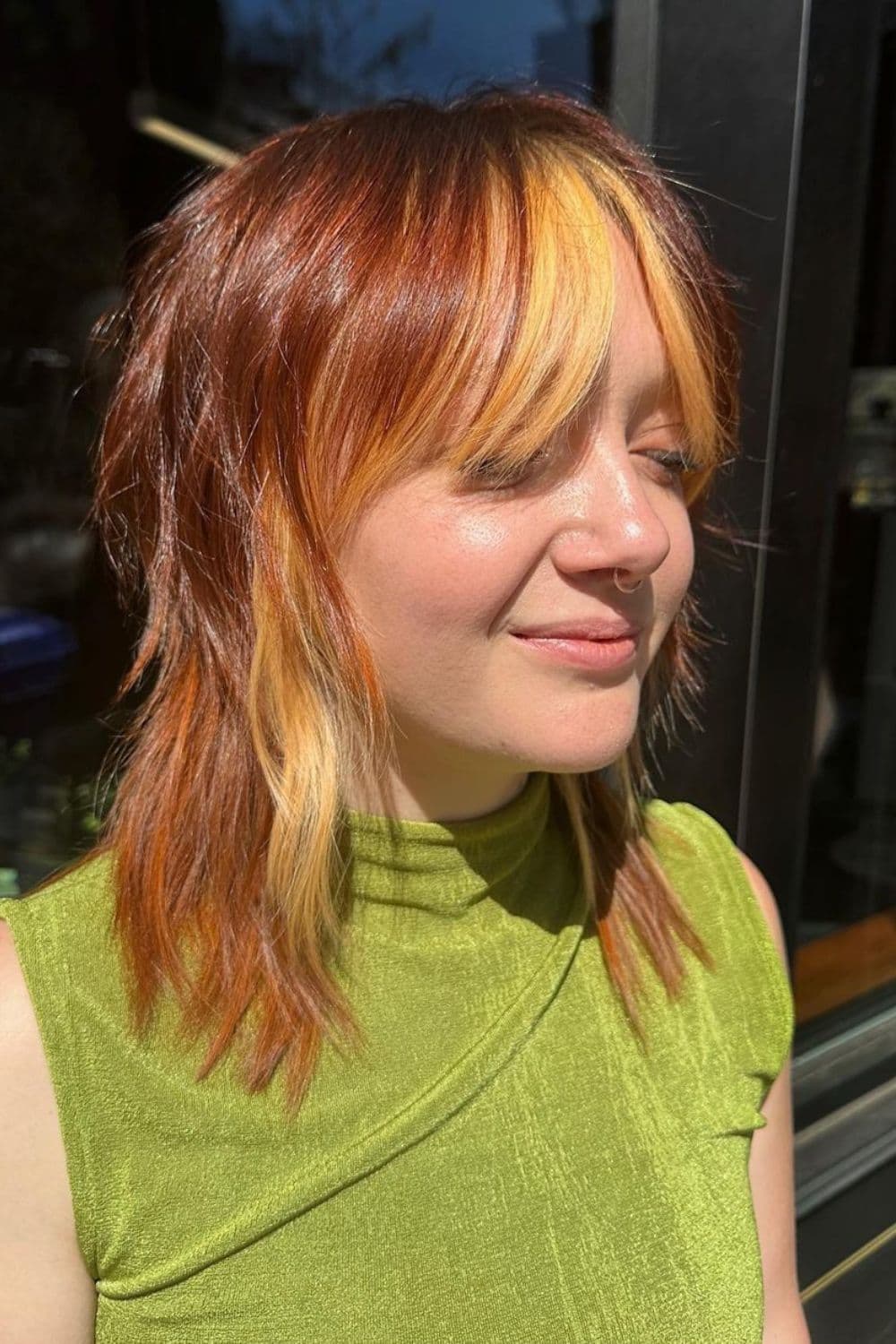 A woman with shaggy copper hair with strawberry blonde highlights.