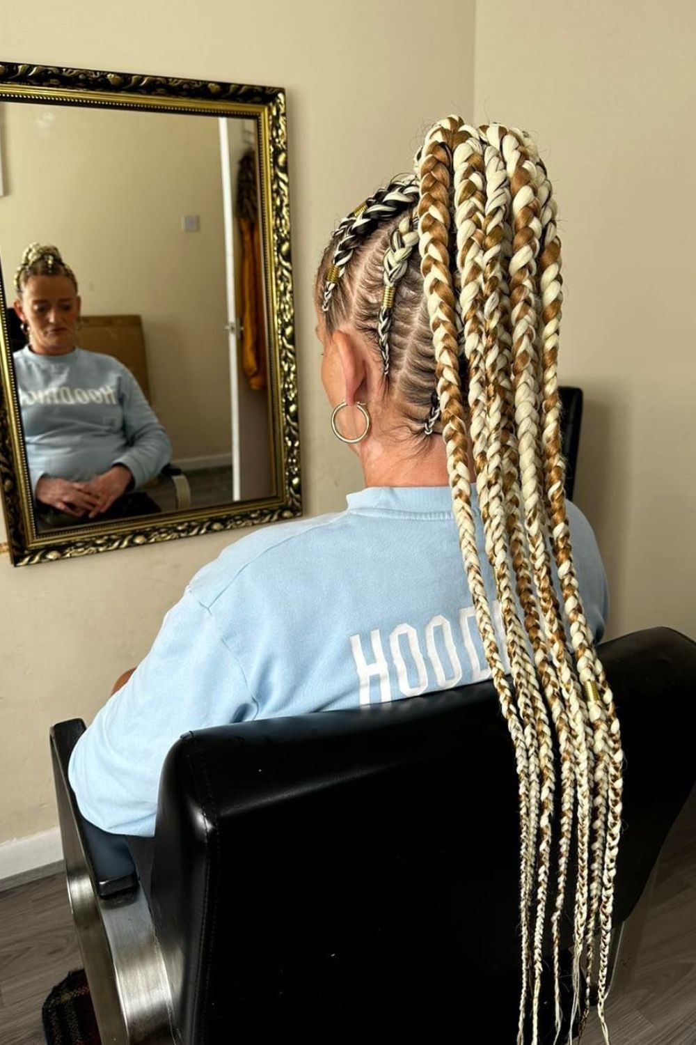 A woman with brown and blonde crochet braid high ponytail.
