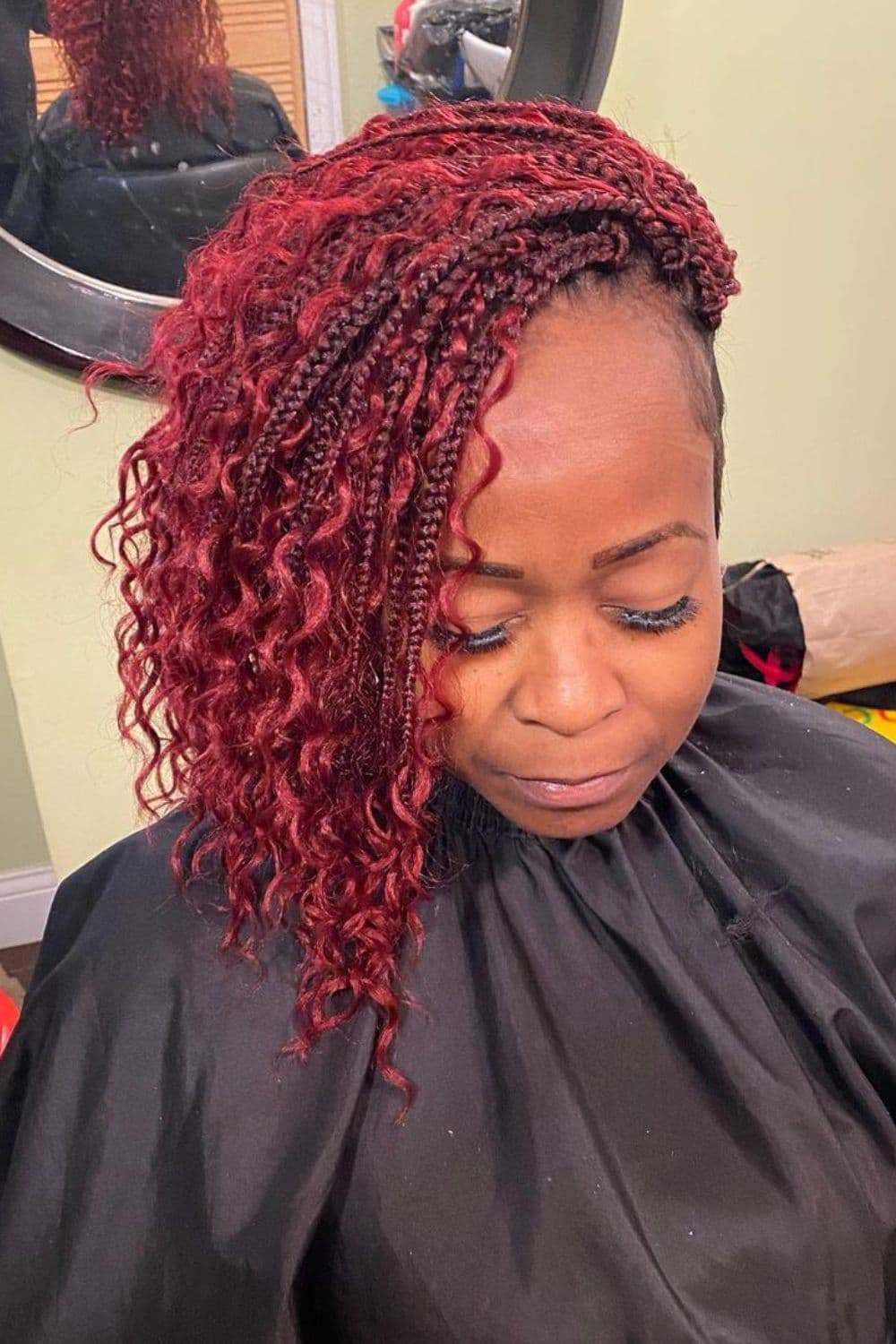 A woman with side-swept red crochet braids.