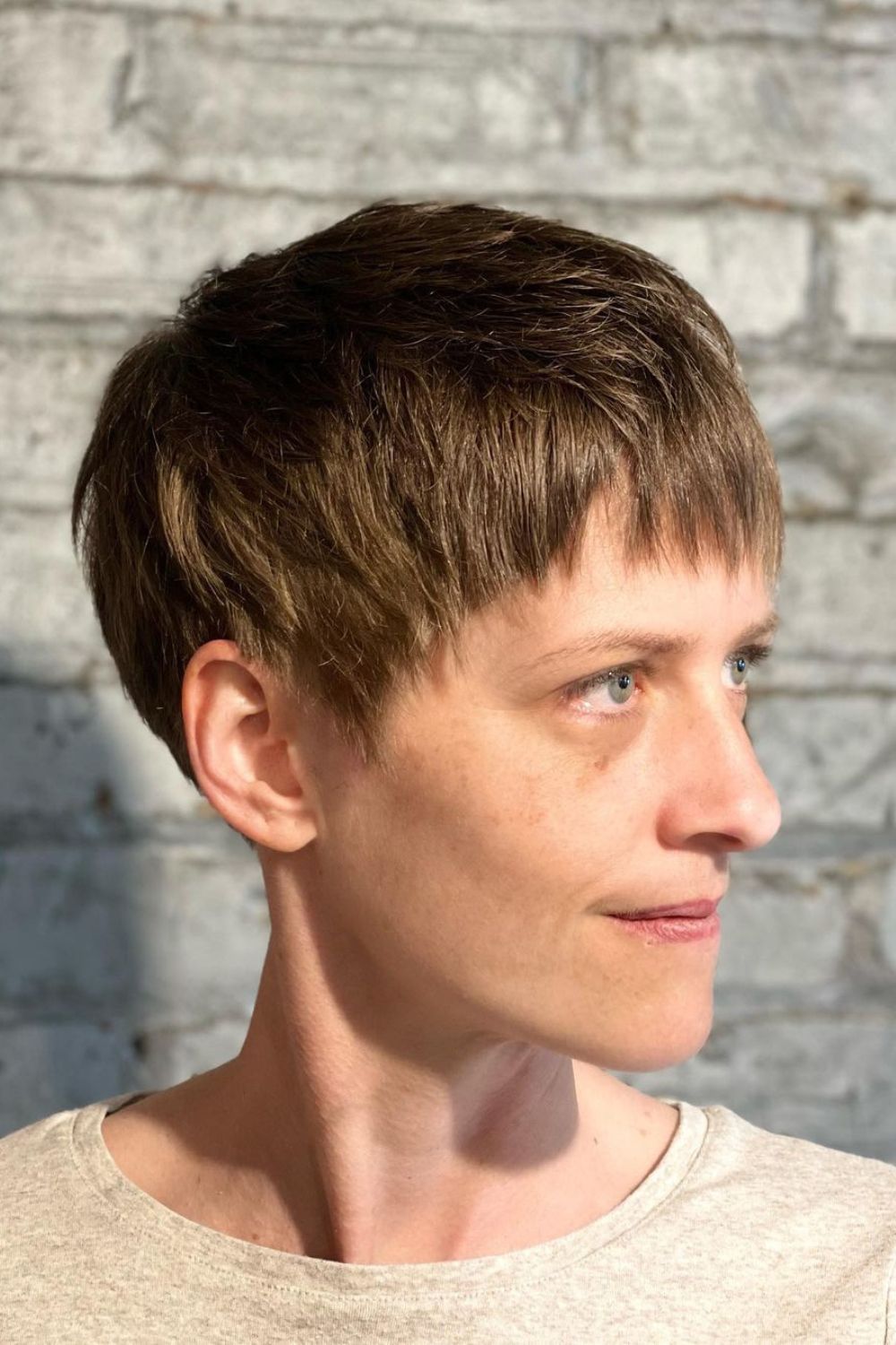 A woman with a brown cropped pixie with choppy bangs.