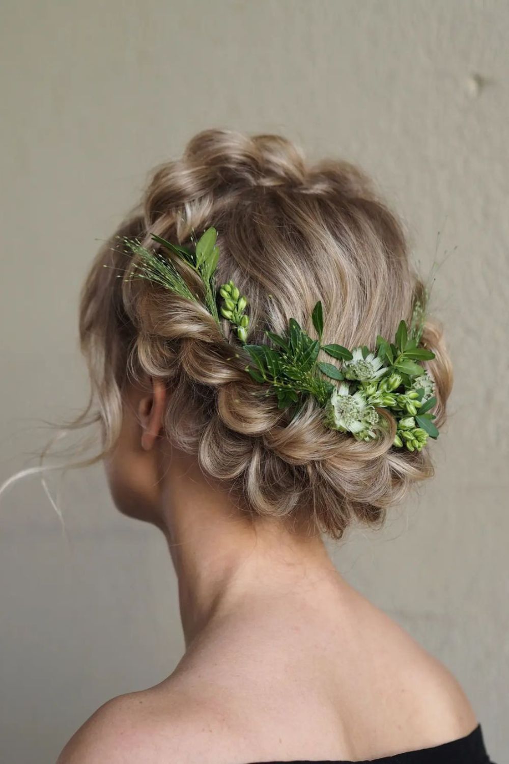 A woman with a blonde crown braid with flower accessories.