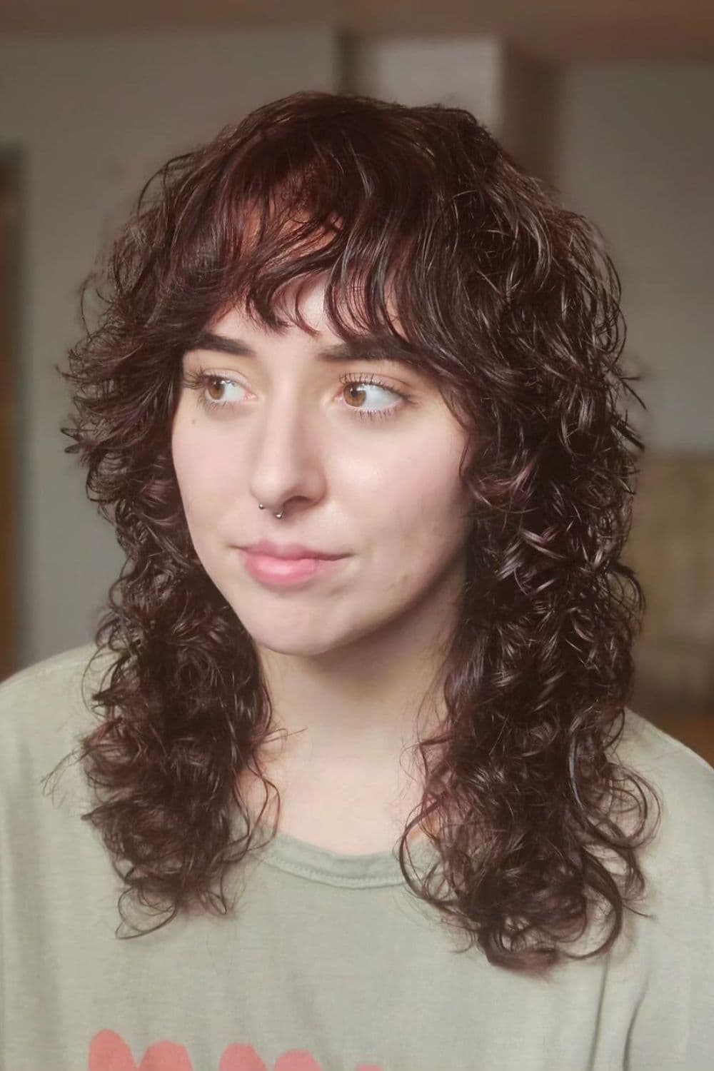 A woman with medium-length curly hair with curly bangs.