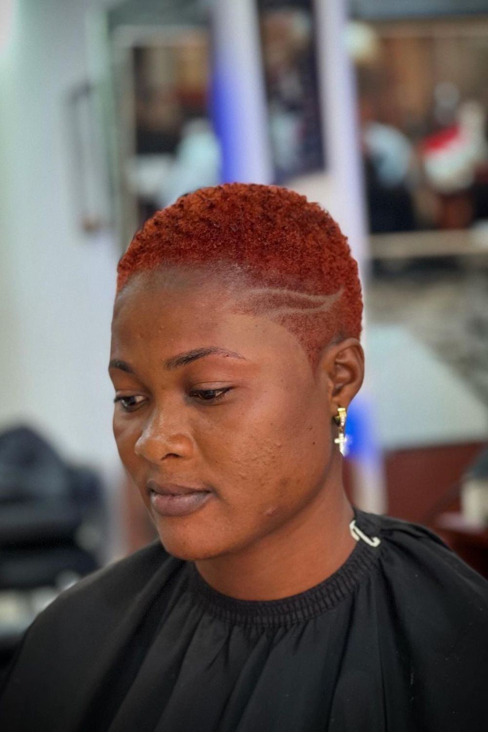 A woman with a red curly top fade.