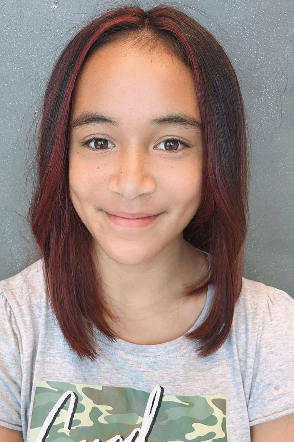 A girl with dark brown long bob with red highlights.