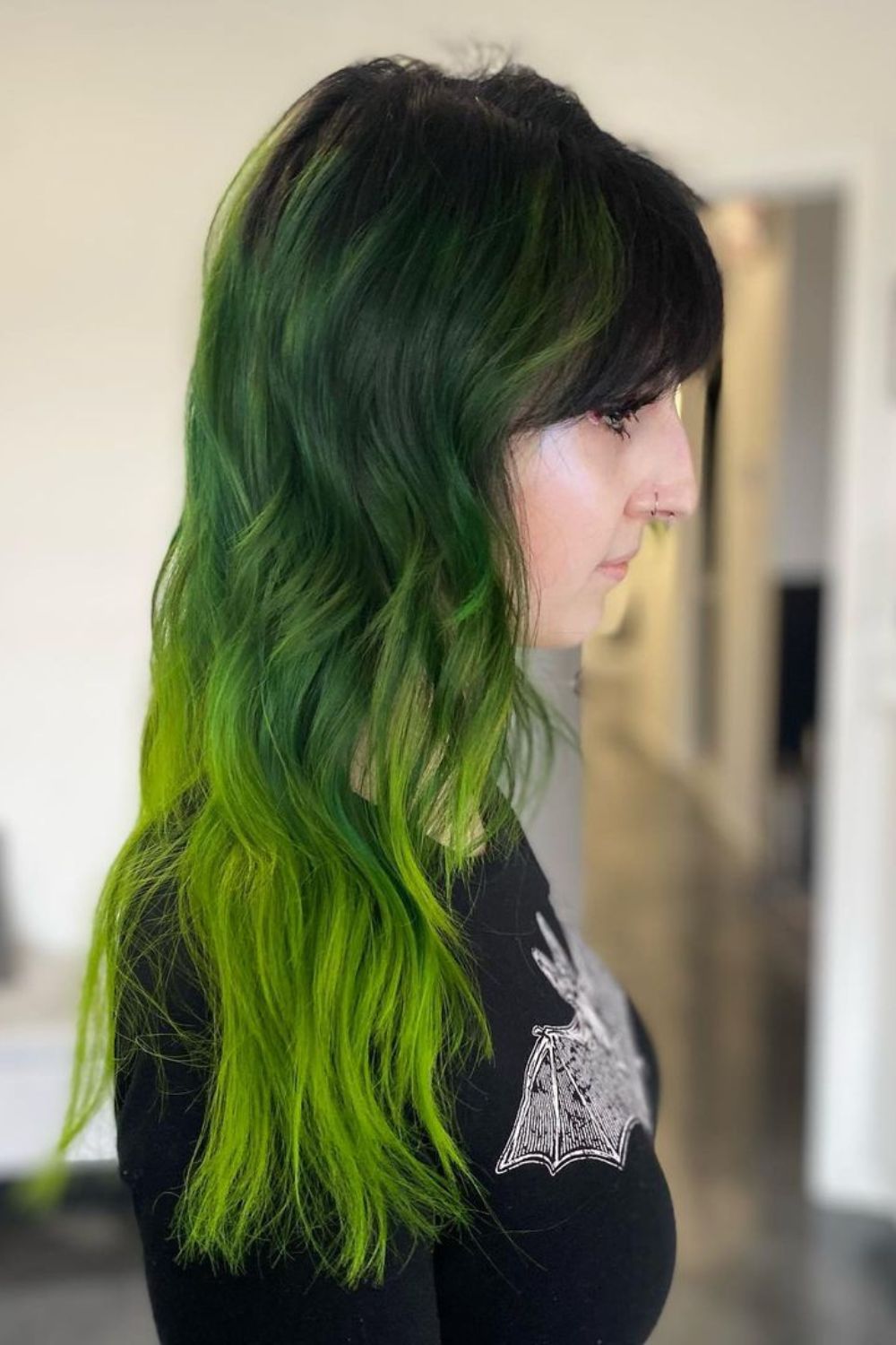 A woman with dark to light green ombre hair.