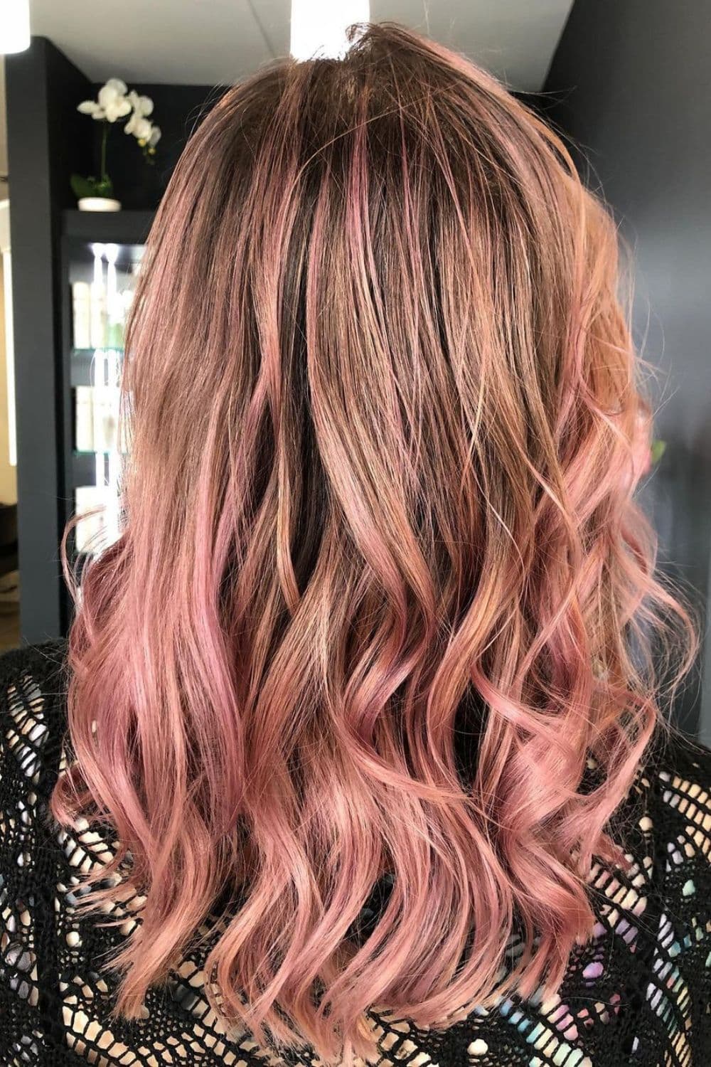 A woman with medium-length dusty pink balayage with curls.