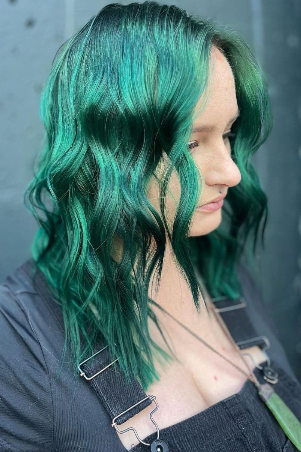 A woman with an emerald green long bob with beach waves.