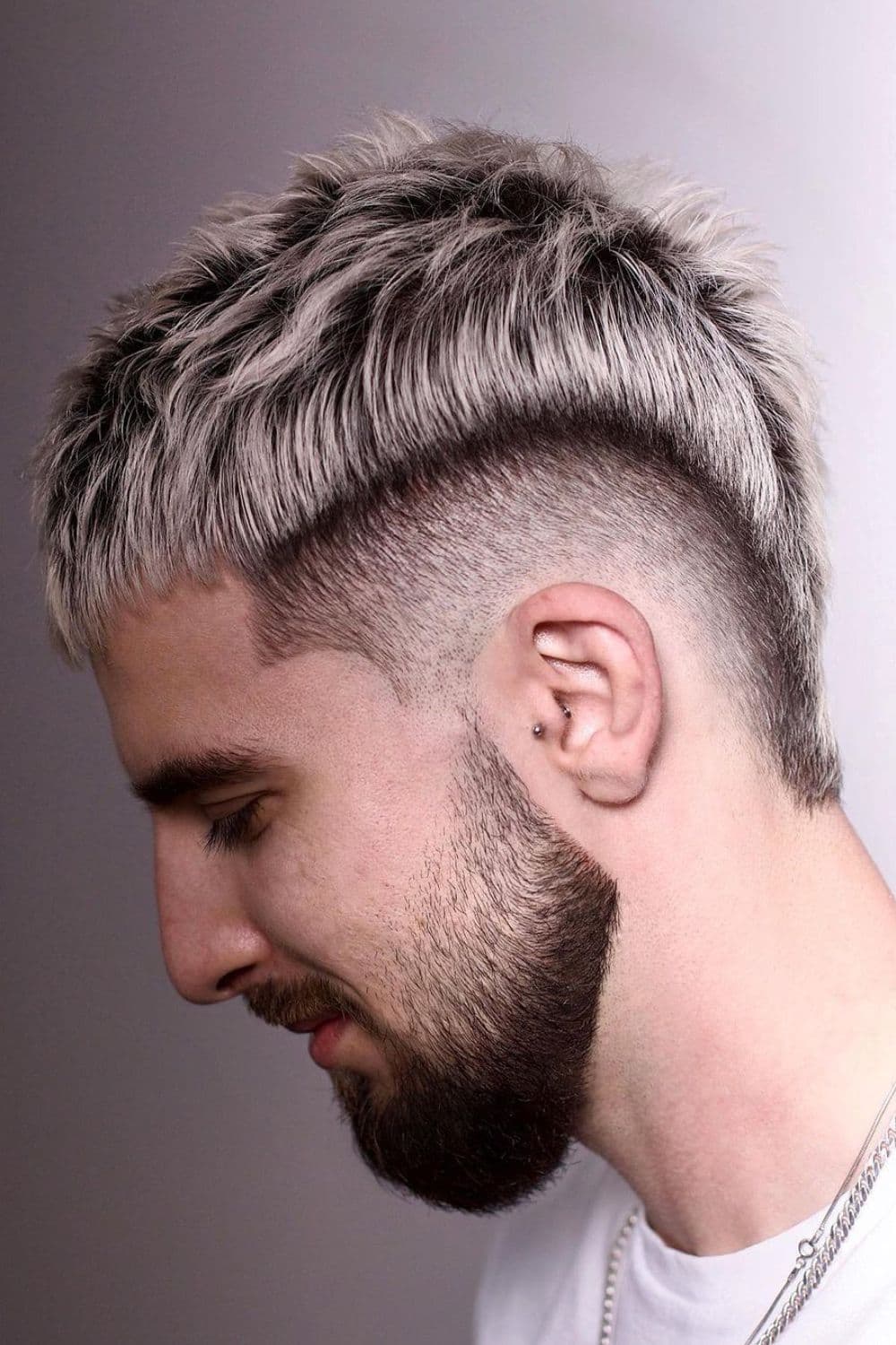 Side view of a man with black and blonde faux hawk fade.