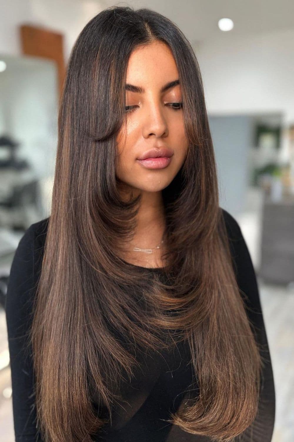 A woman with a long caramel beige feather cut balayage.