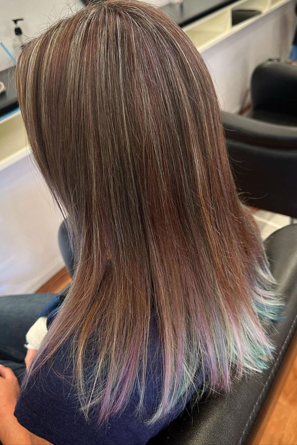 A woman with a feathered cut violet and emerald ombre.