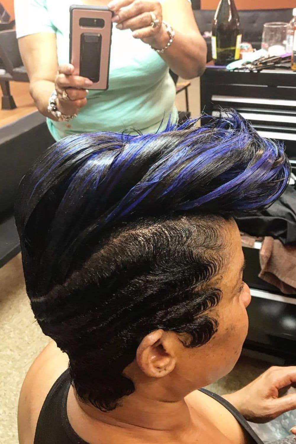 A black woman with a finger wave mohawk with blue highlights.