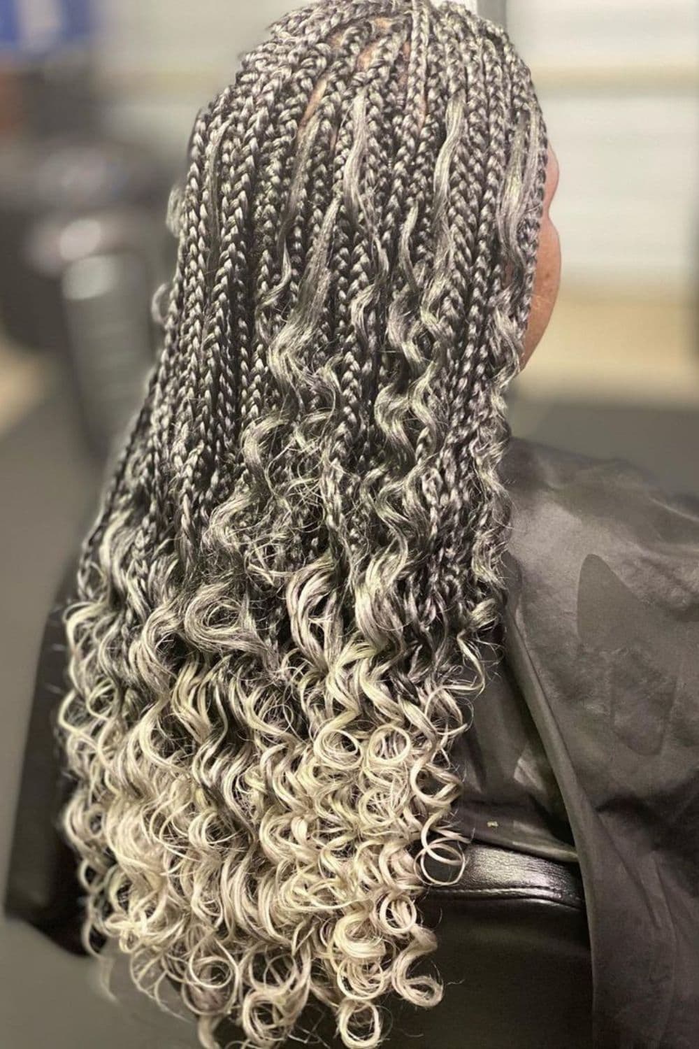 A woman with long gray goddess braids with curly ends.