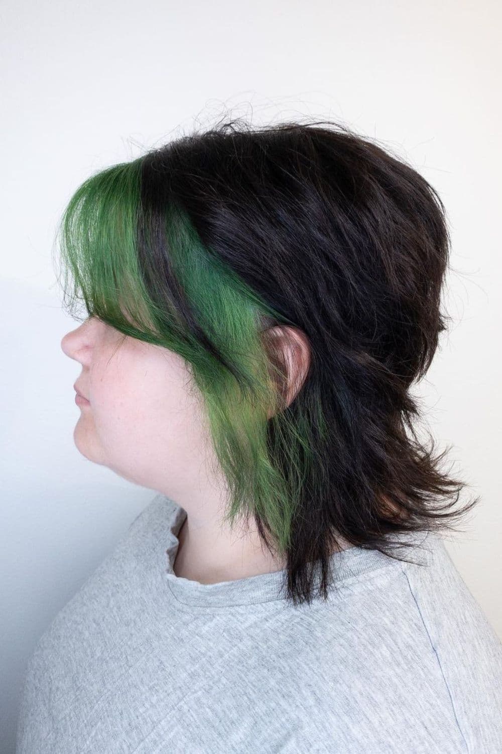 A woman with a short green money piece on black hair.