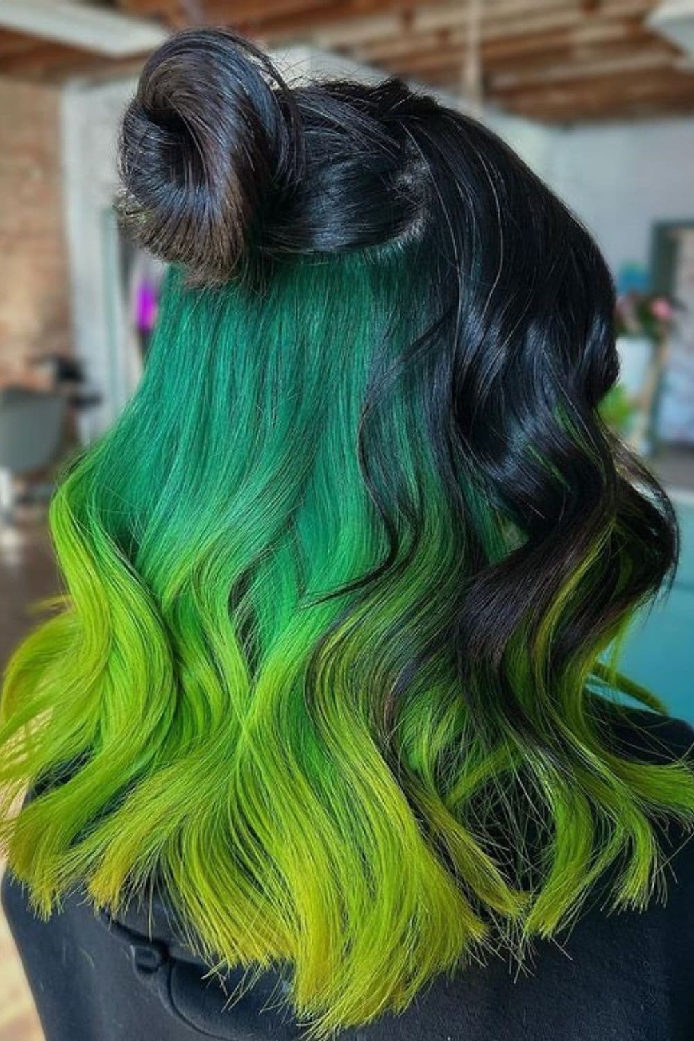 A woman with a half-up half-down green ombre hair.