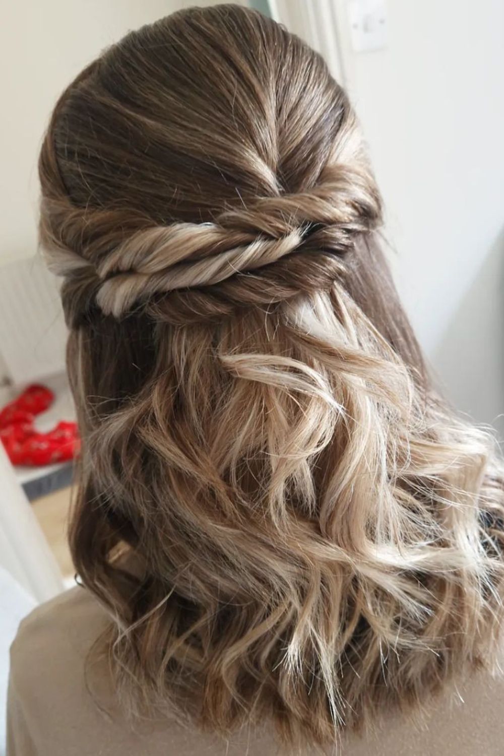 A woman with a medium-length half up half down twisted updo.