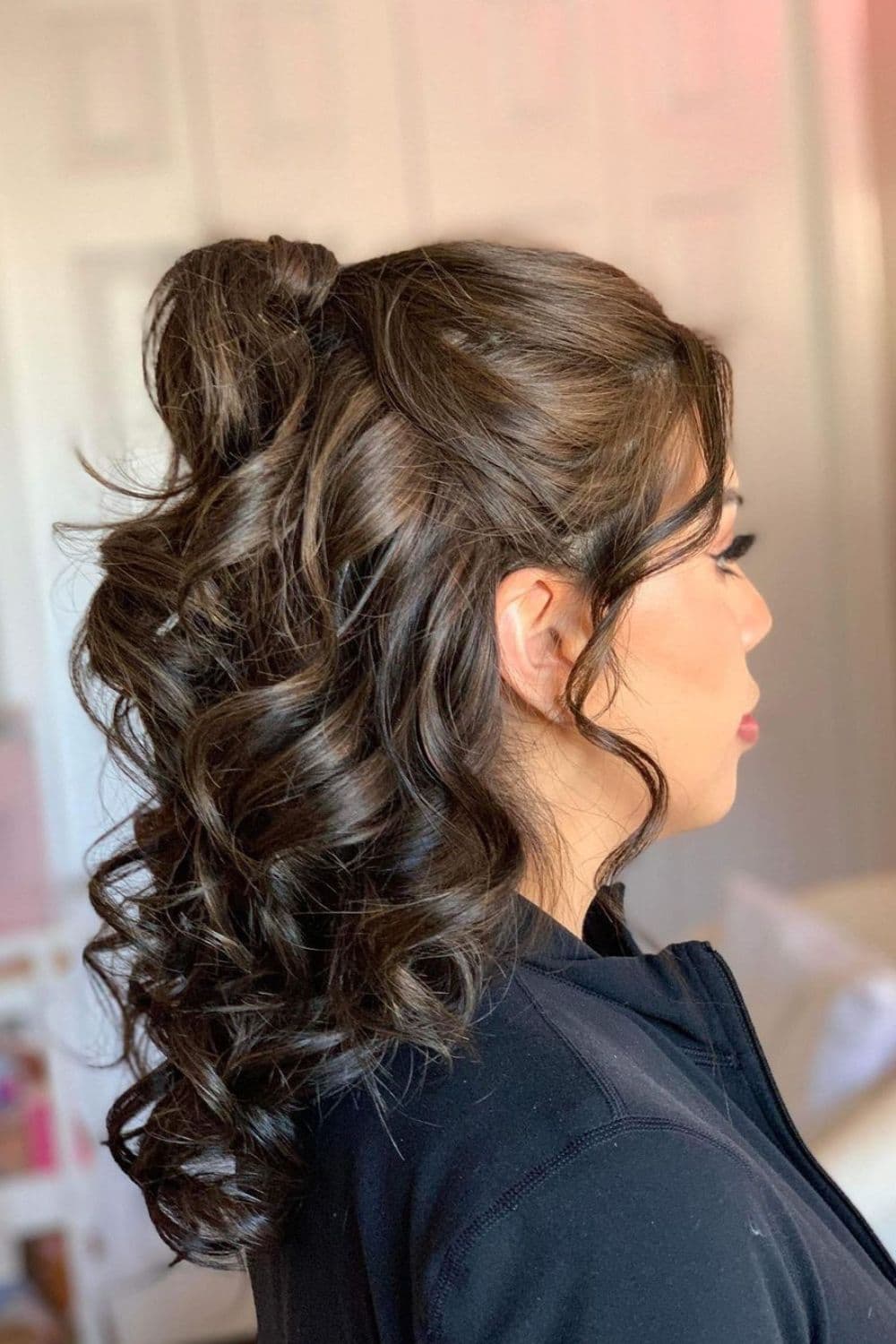 A woman with a brown half-up high ponytail with big curls.