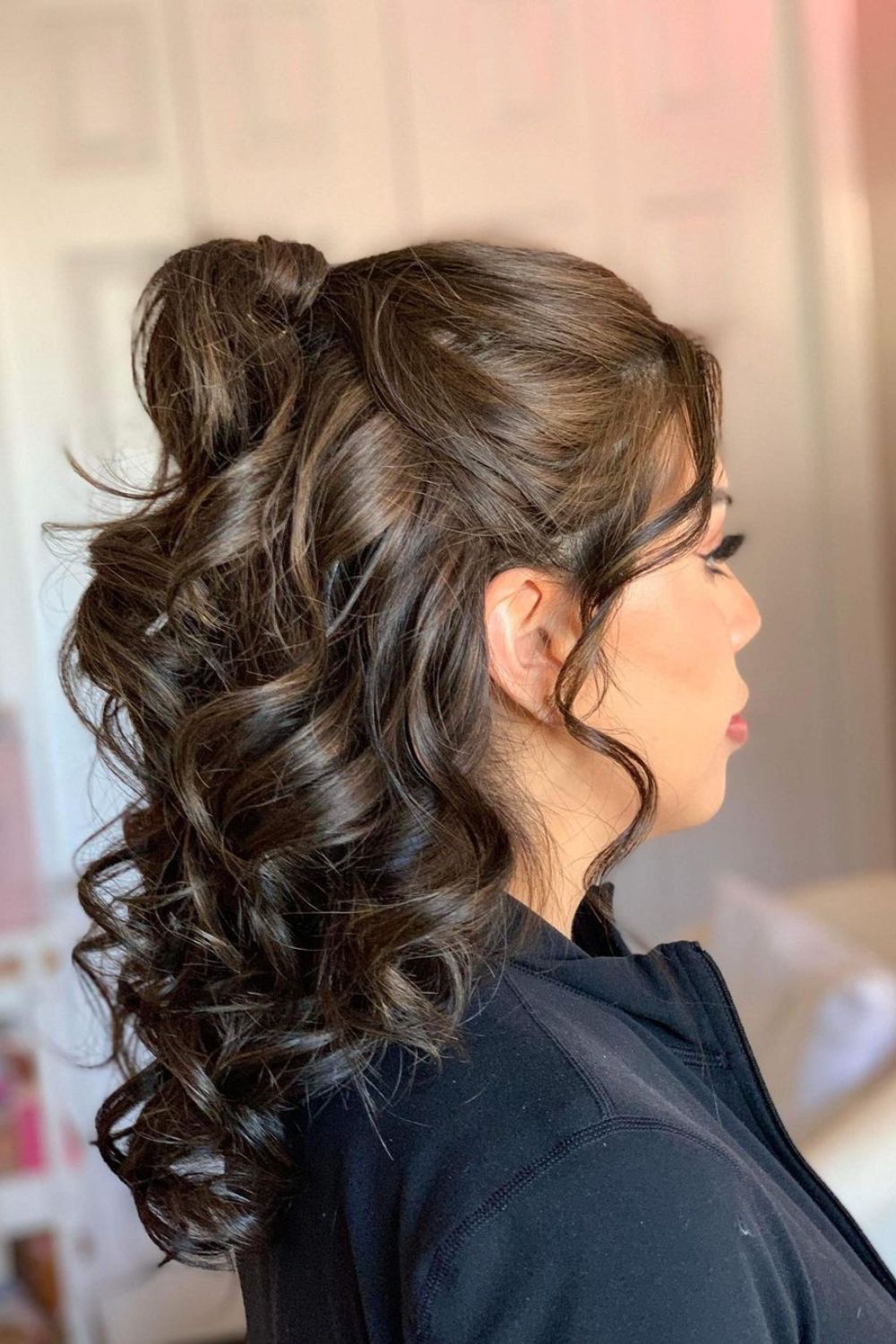 A woman with a half up high ponytail with curls.