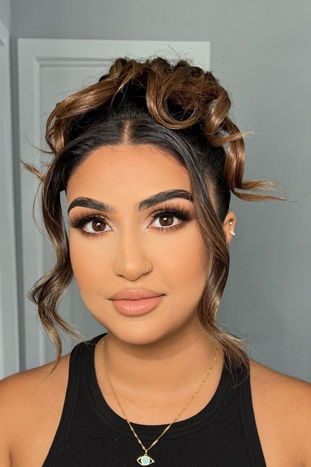 A woman with a brown high bun with face-framing pieces.
