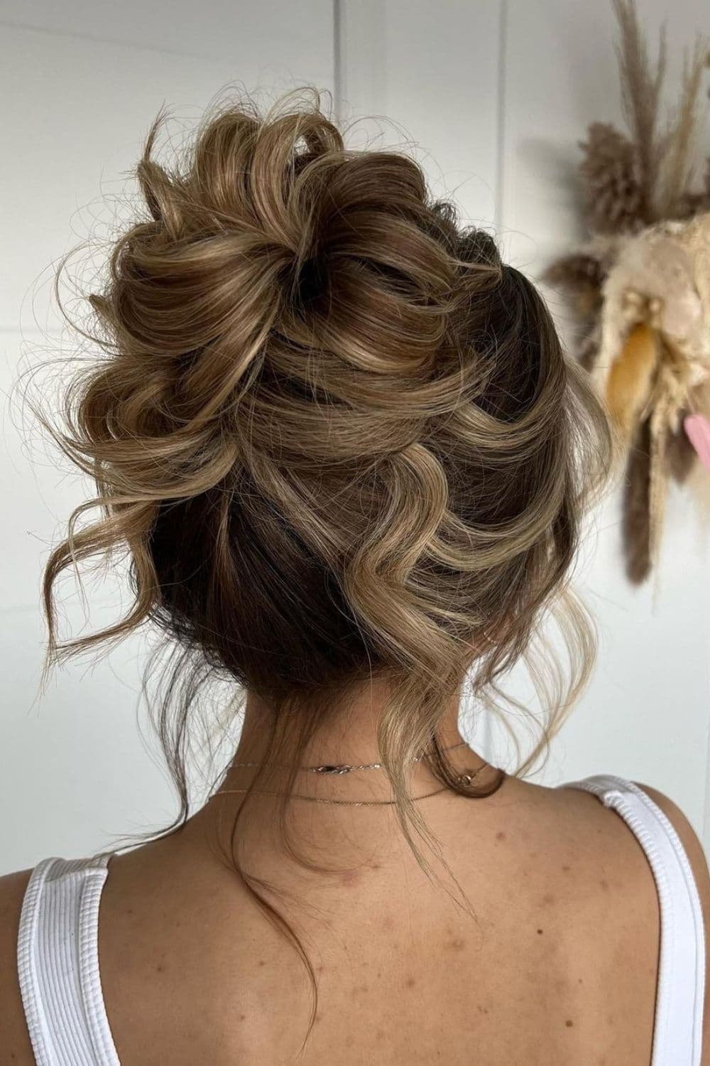 A woman with a high bun with loose curls.