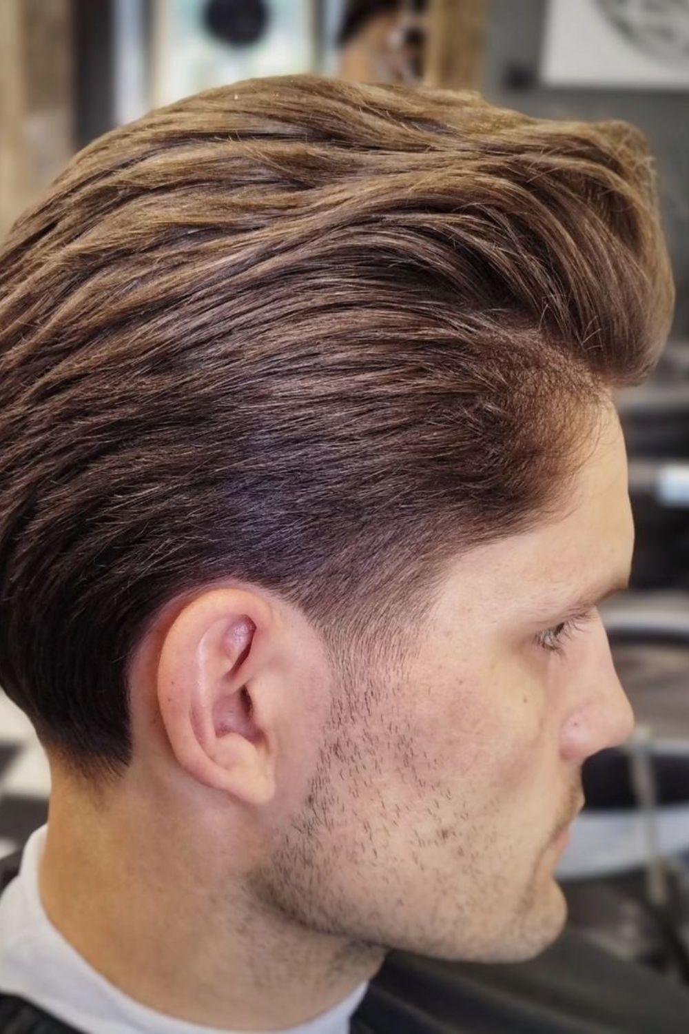 A man with a brown high-volume slick back hair.