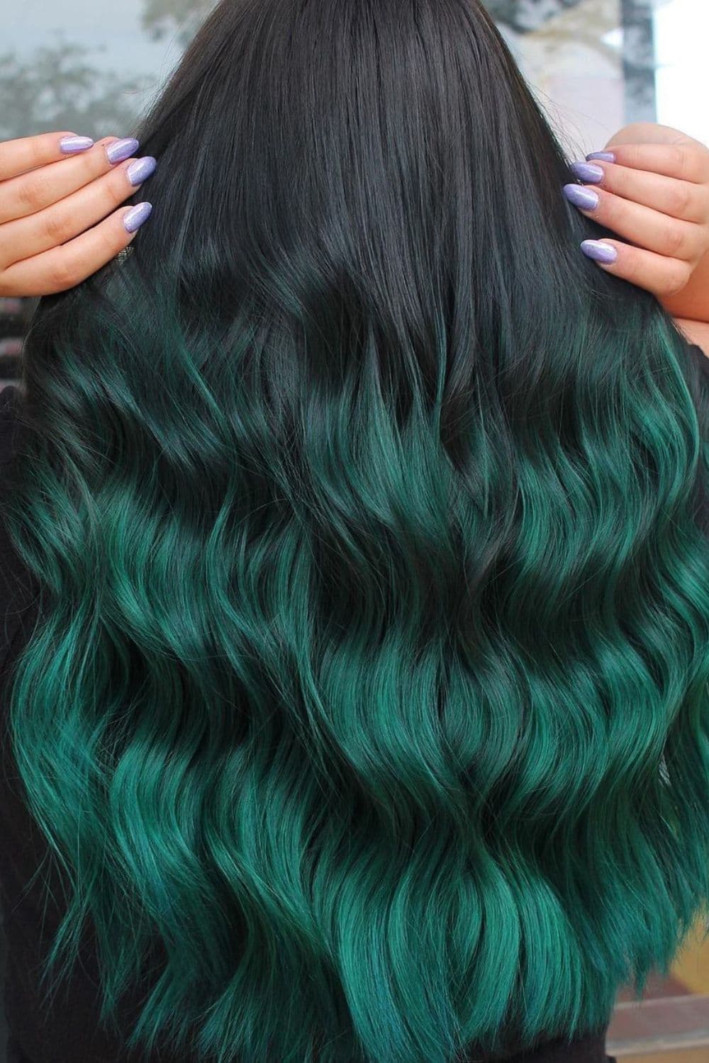 A woman holding her hunter green ombre hair.