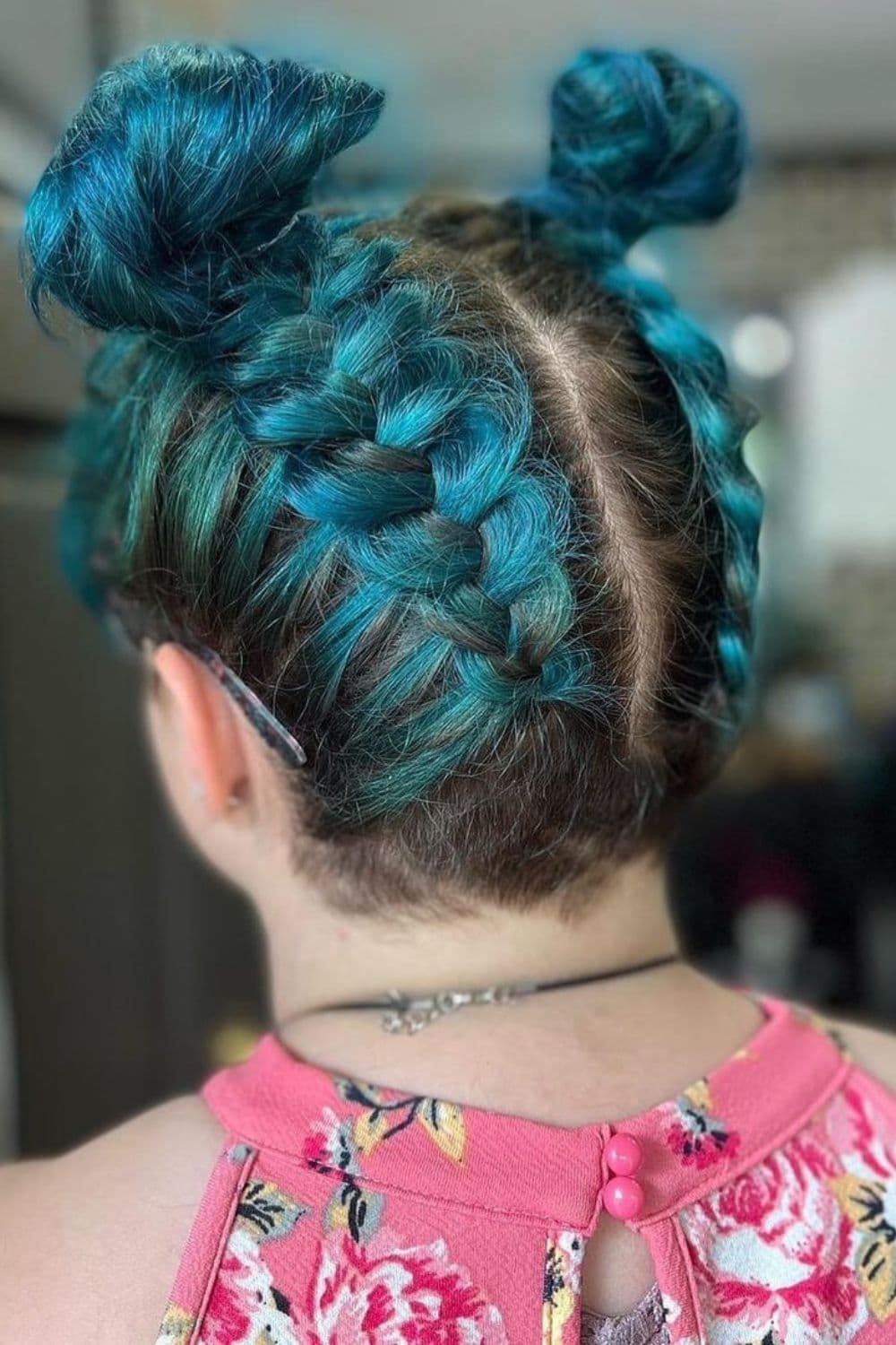 A woman with emerald green inverse braids with space buns.