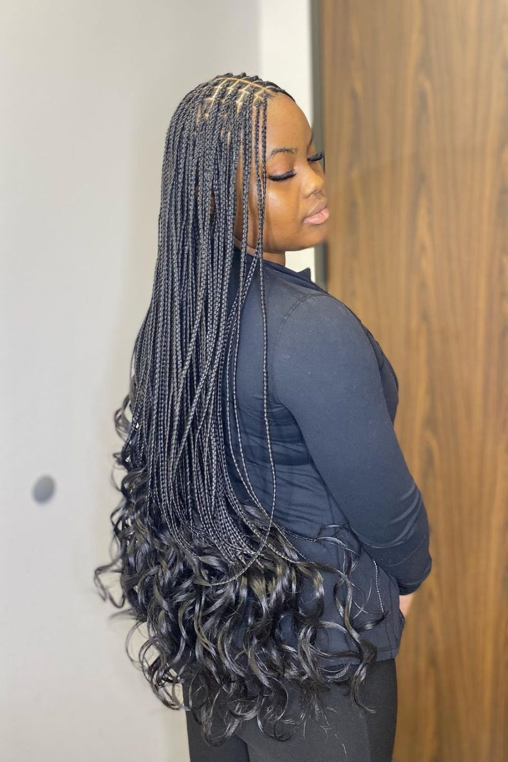 A woman with long black knotless braids with French curl.