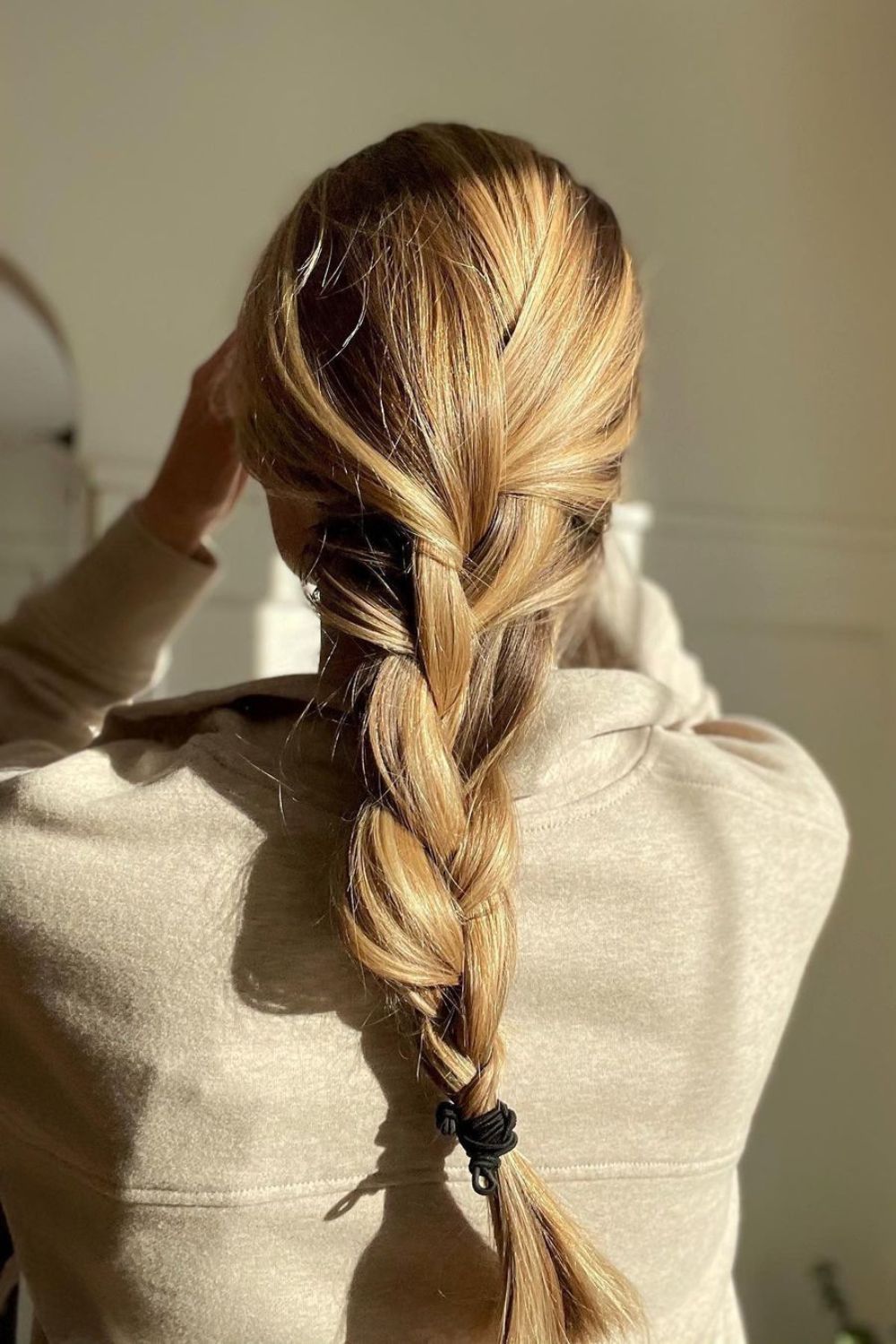 A woman with a long blonde loose French braid.