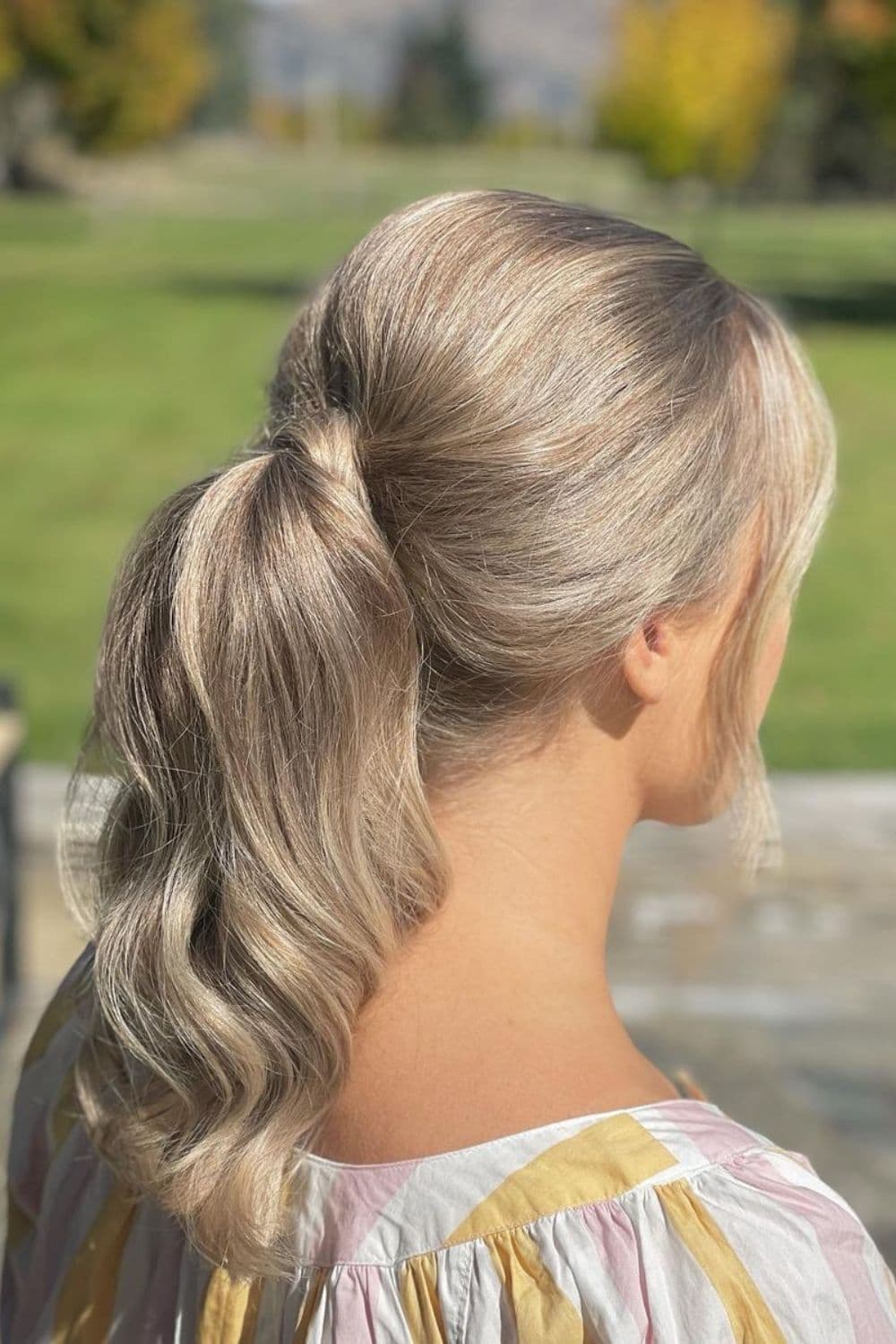 A woman with a blonde loose low ponytail.
