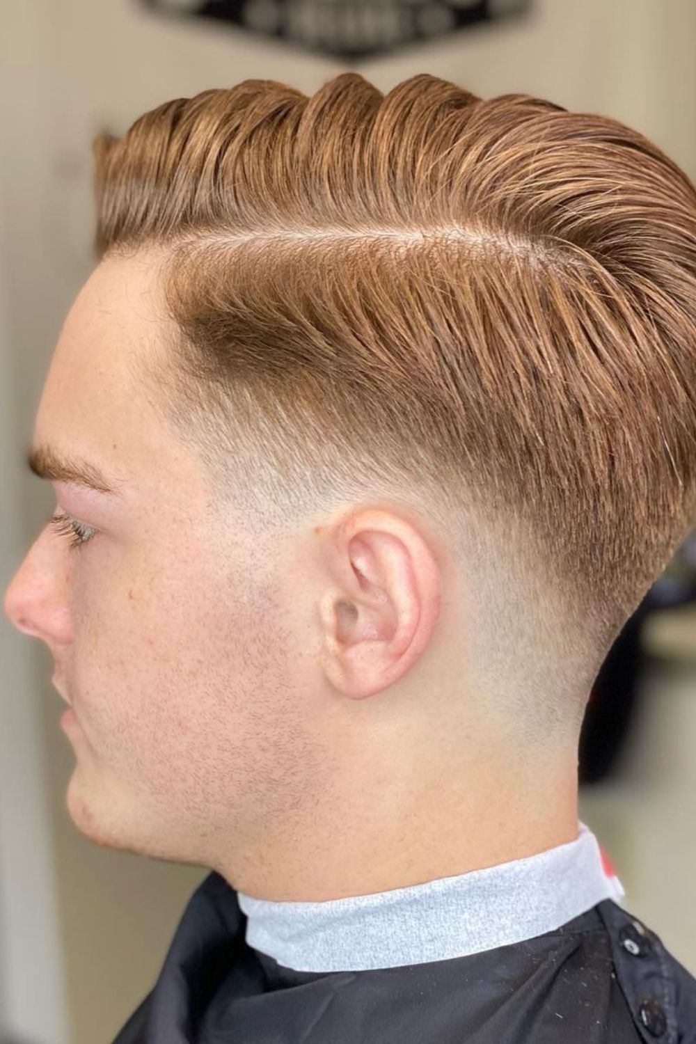 A man with a blonde low fade comb-over.