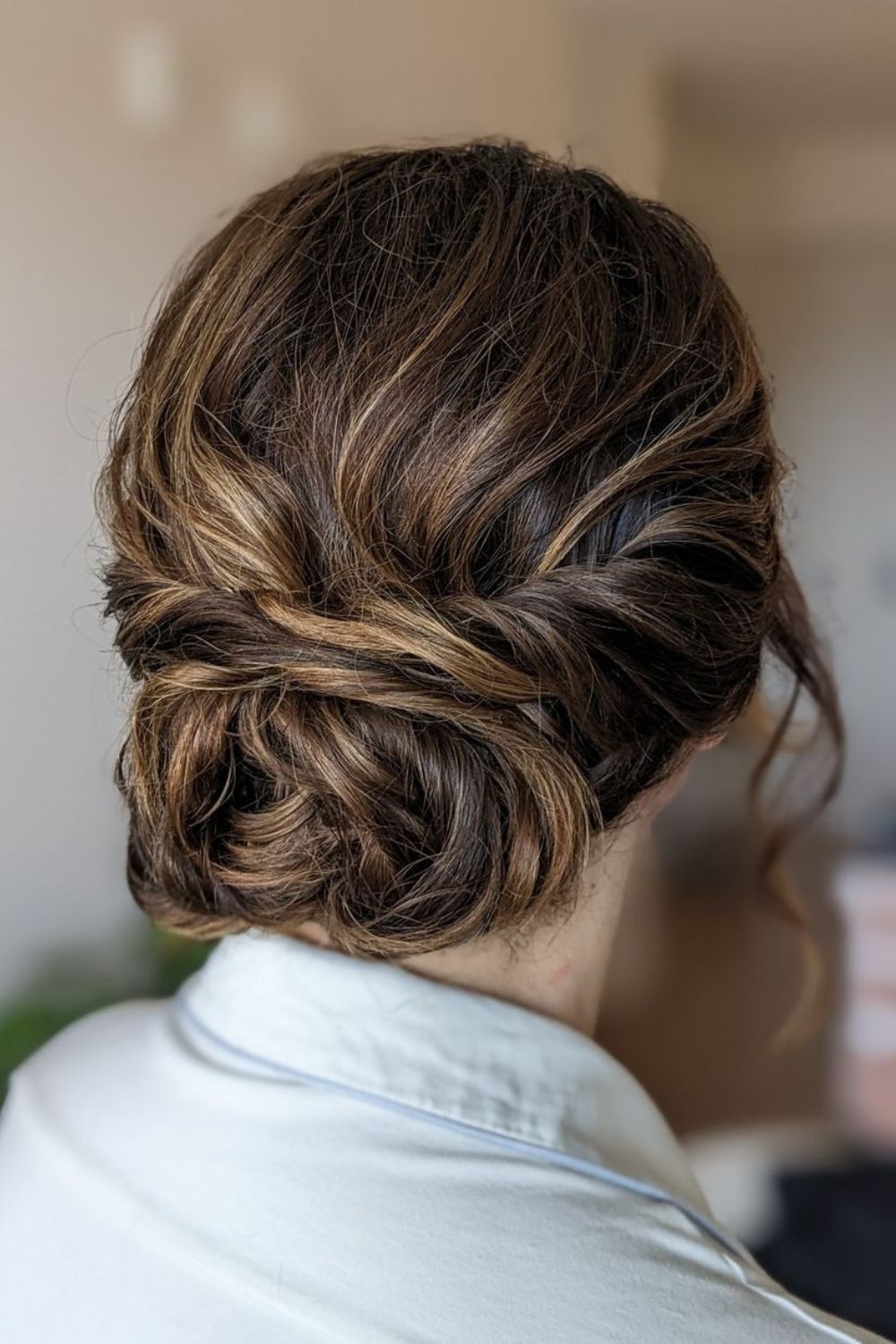 A woman with a low messy bun with highlights.