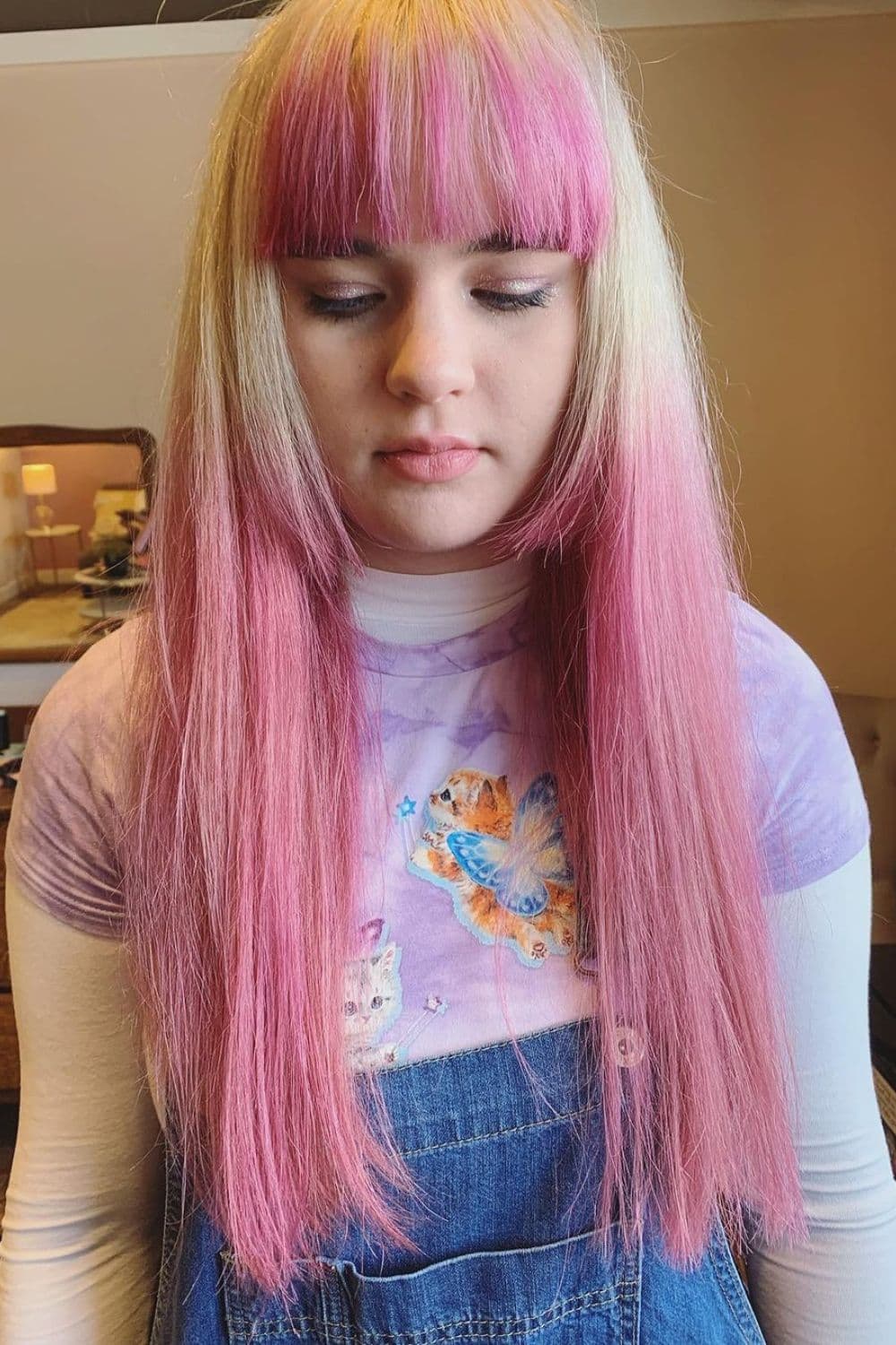 A woman with long blonde and pink hair and medium-length blunt bangs.