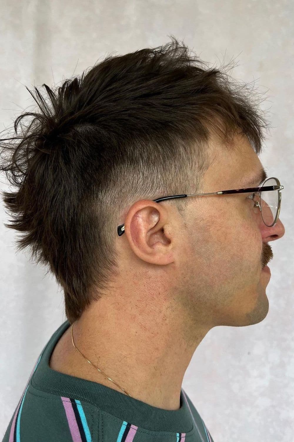 A man wearing eyeglasses with a black modern mullet.