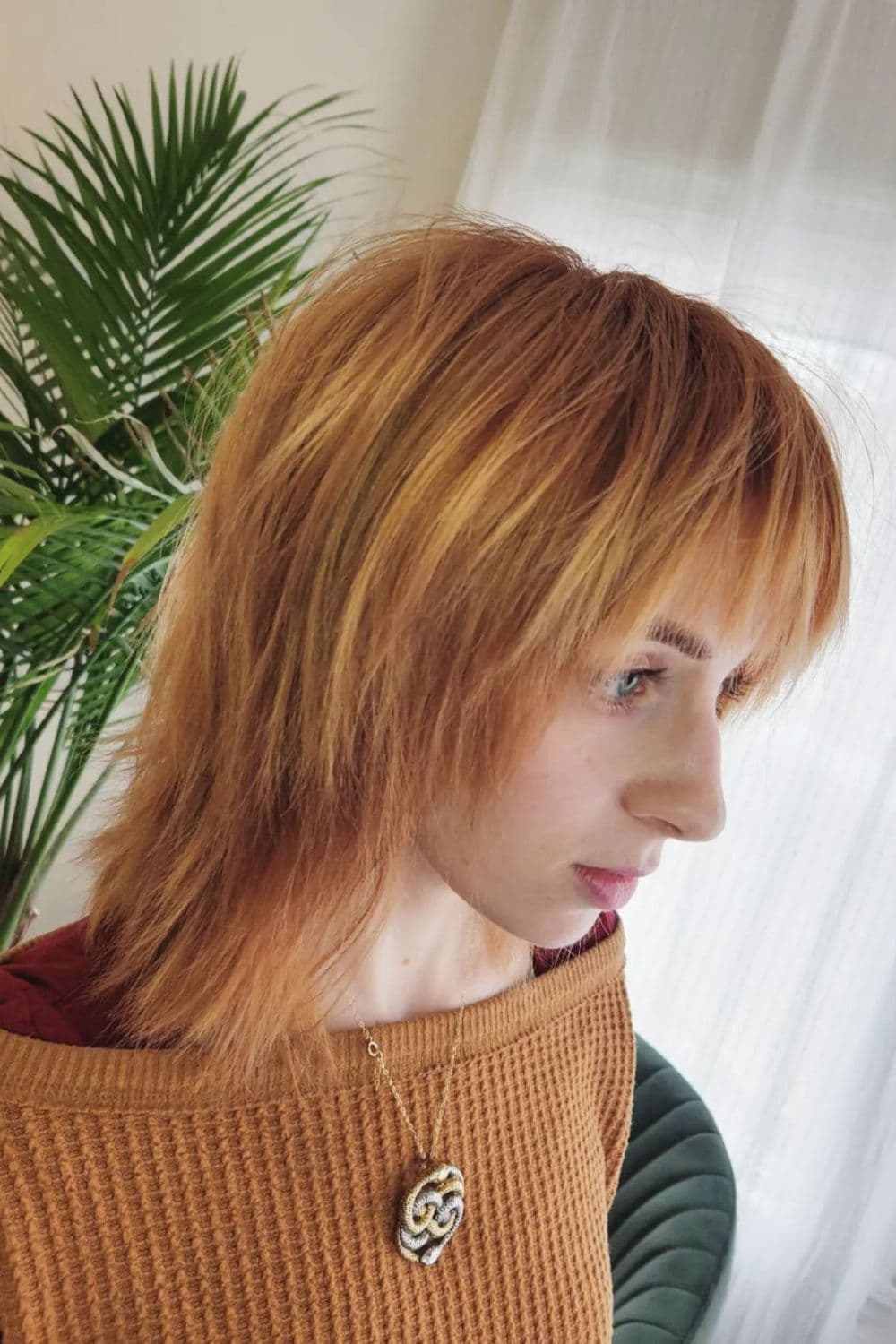 A woman with nape-length feather cut with bangs.