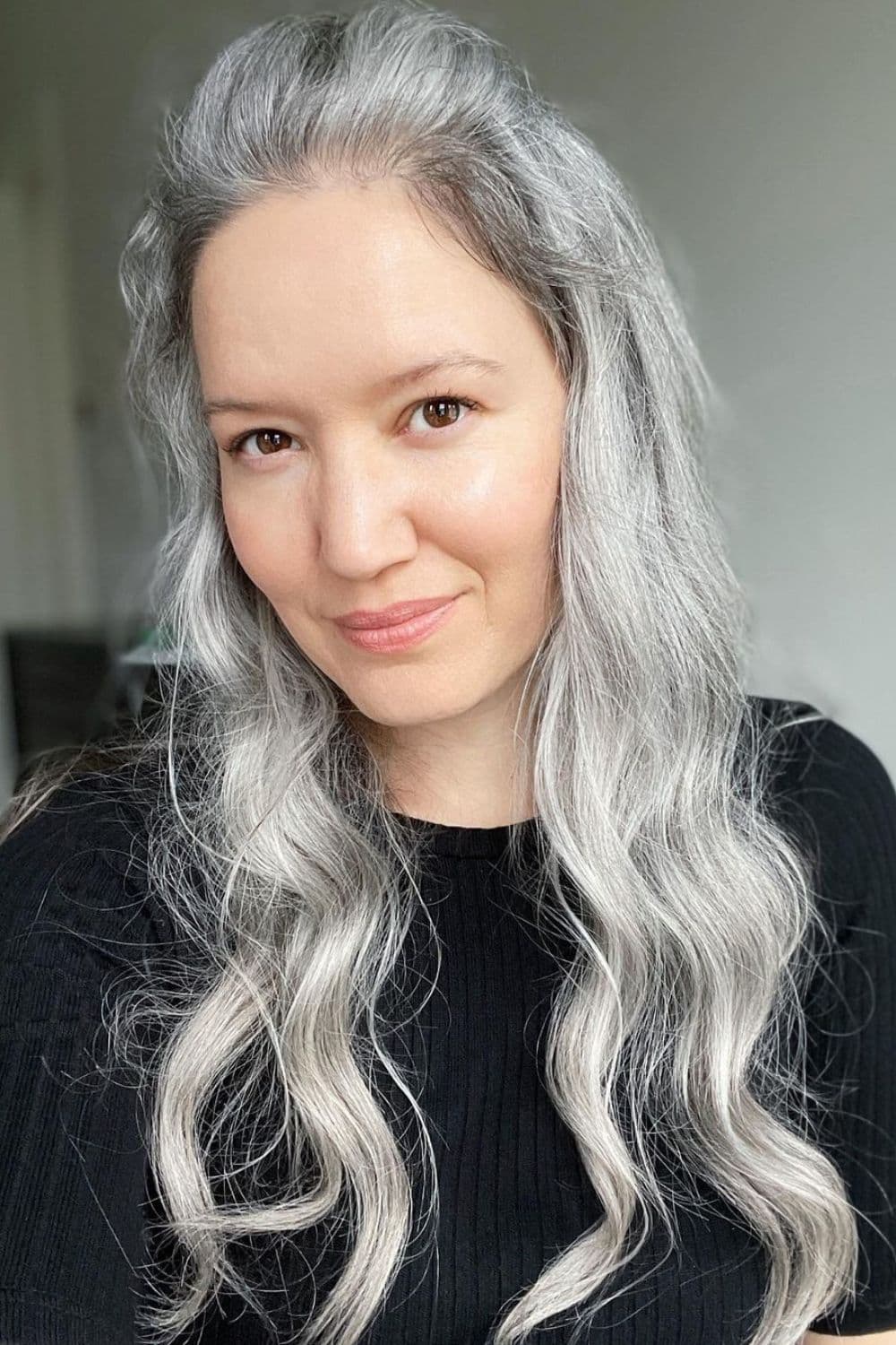 A woman with a long wavy natural silver hair color.