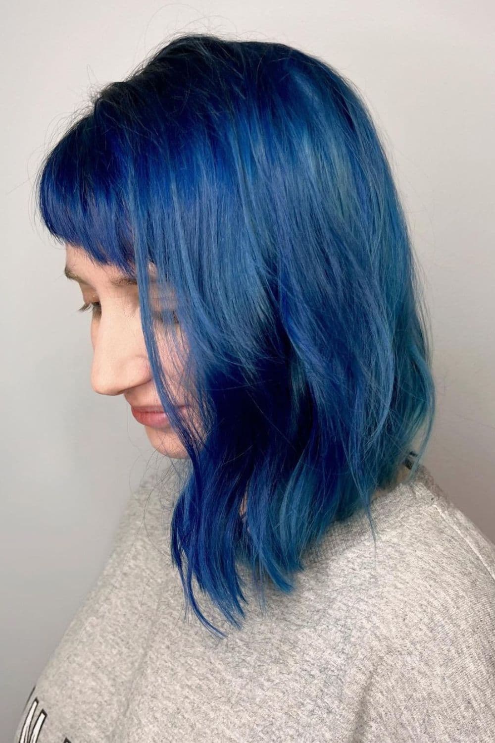 A woman with a navy blue long bob with aqua highlights.