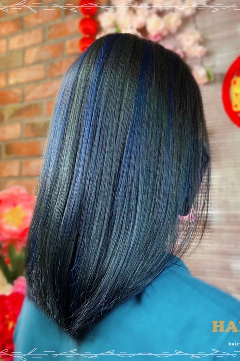 A woman with medium-length blue black hair with ocean blue highlights.
