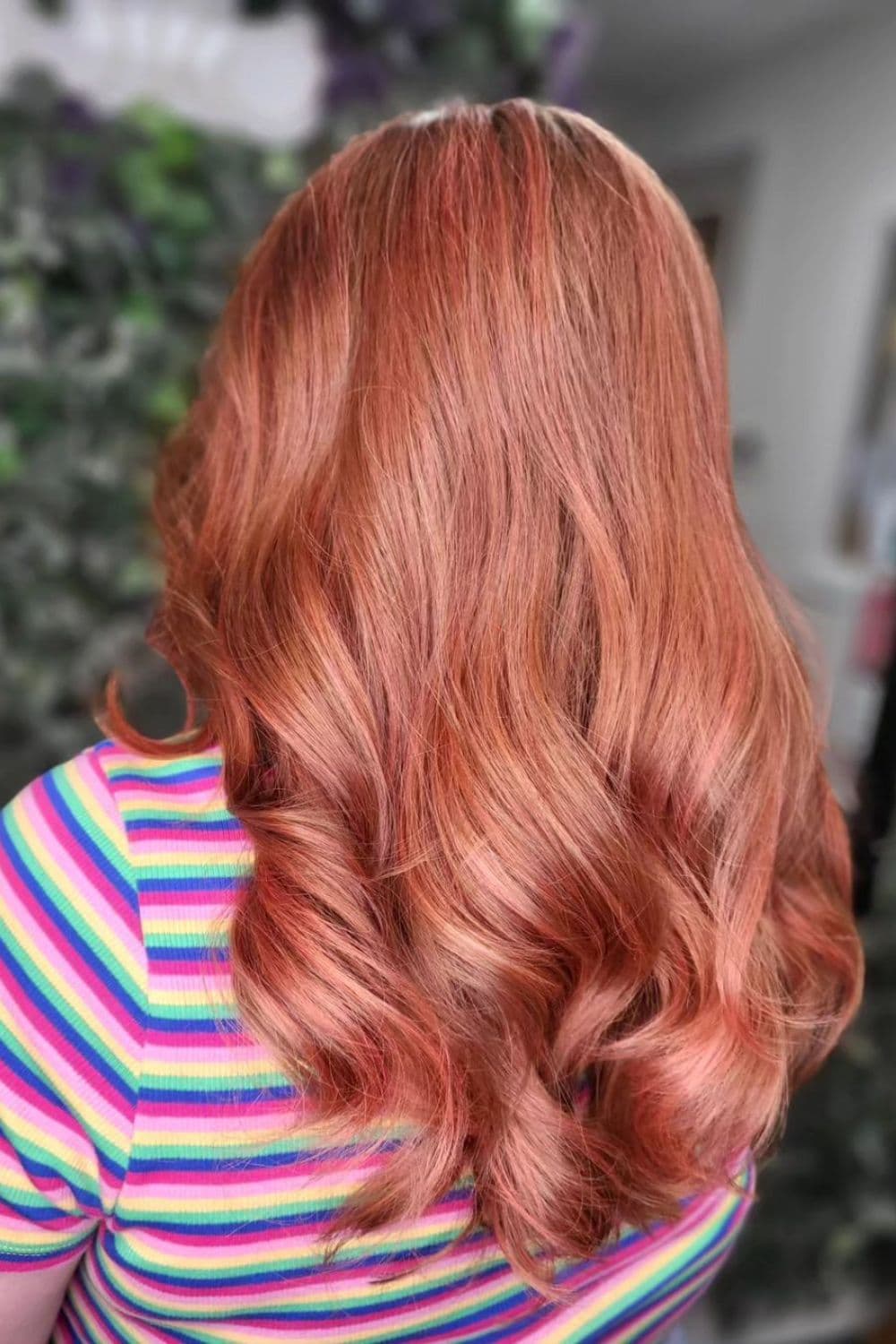 A woman with long wavy peachy copper red balayage.
