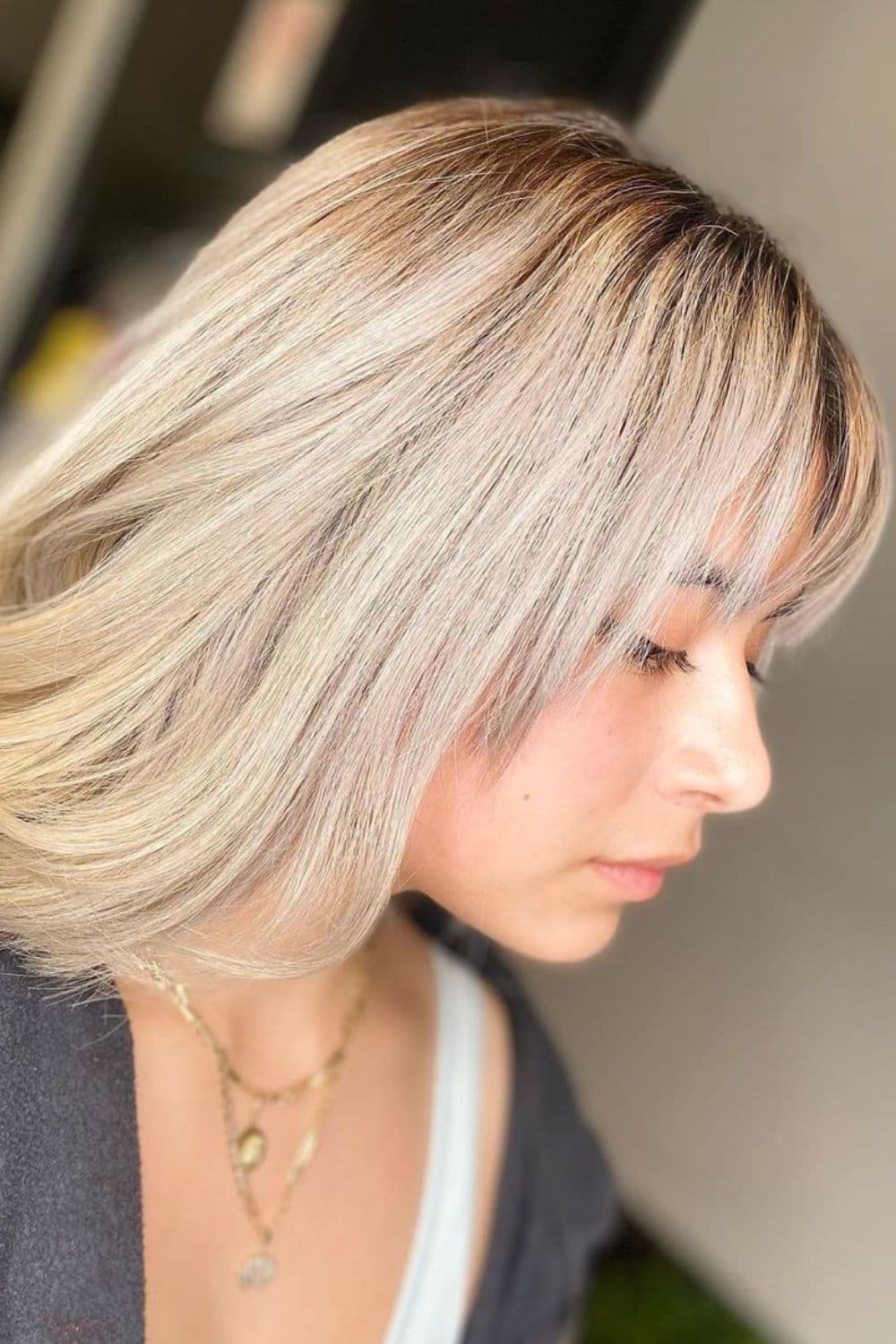 A woman with pearl-toned platinum blonde hair with bangs.