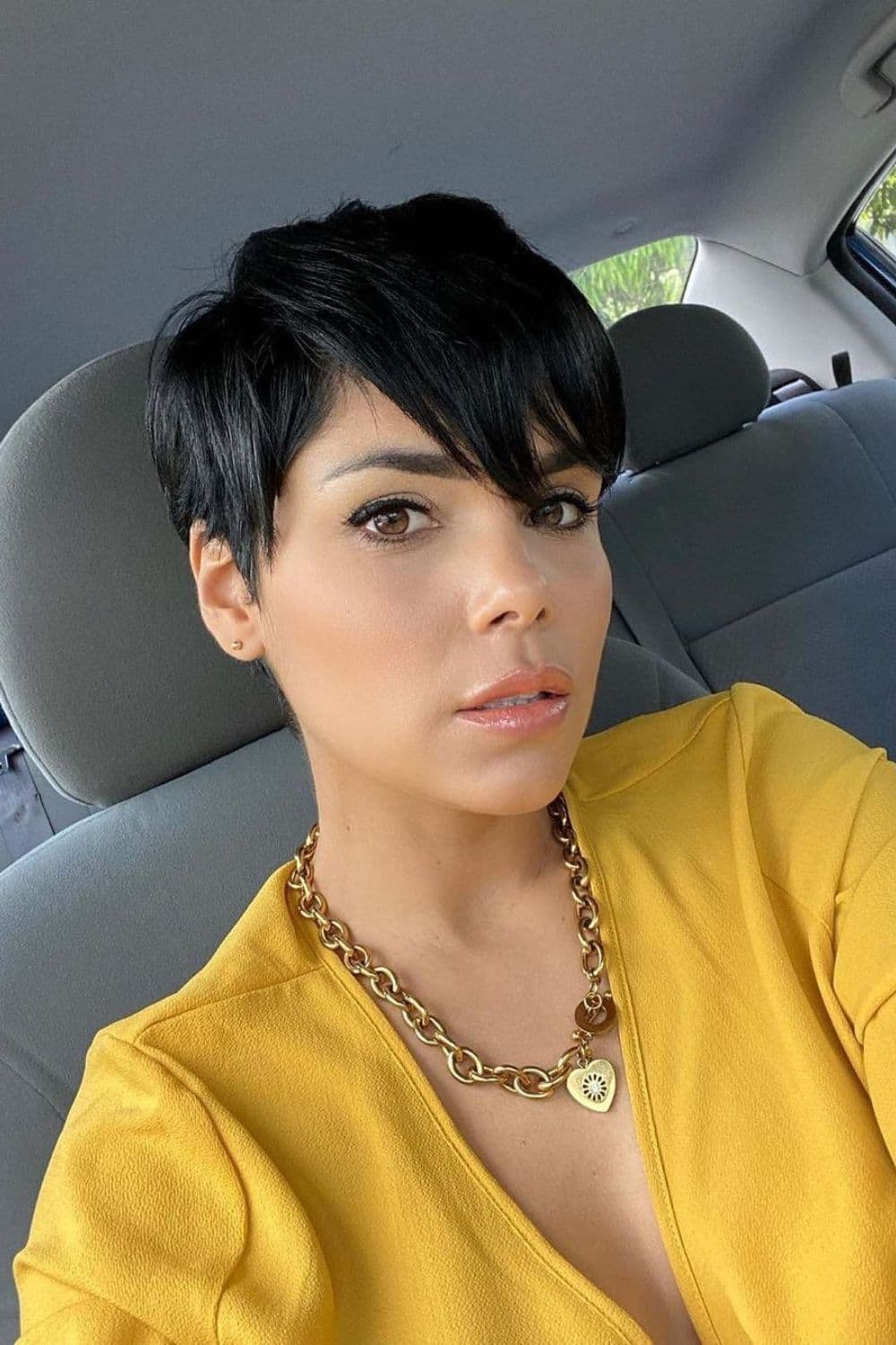 A woman with a black pixie cut with long side bangs.