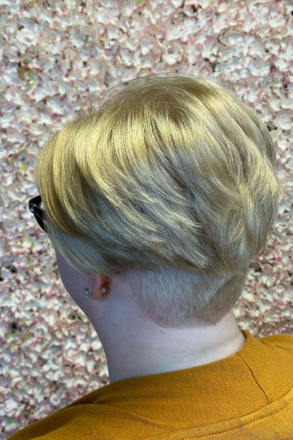 A woman with a blonde pixie with a nape undercut.