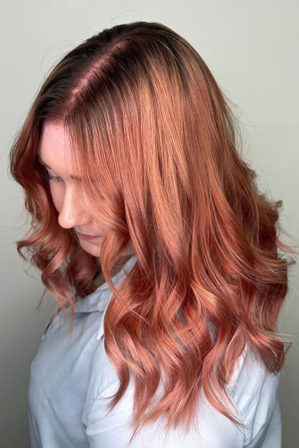 A woman with medium-length rose gold hair with curls.