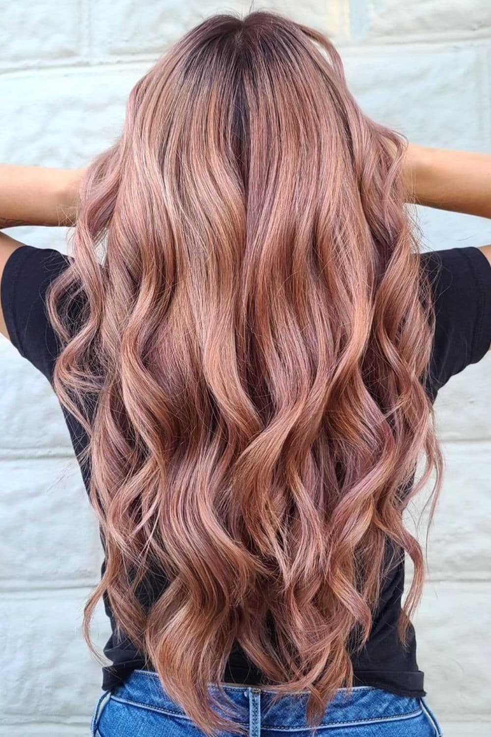 A woman with a long rose gold hair with big curls.