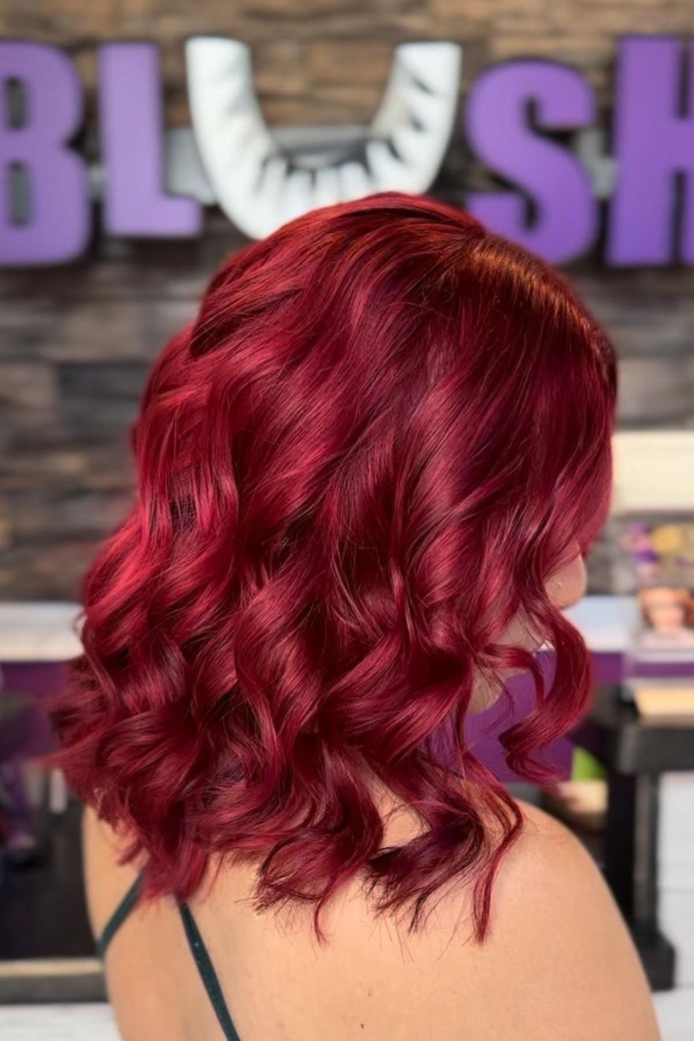 A woman with curled ruby red lob hair.