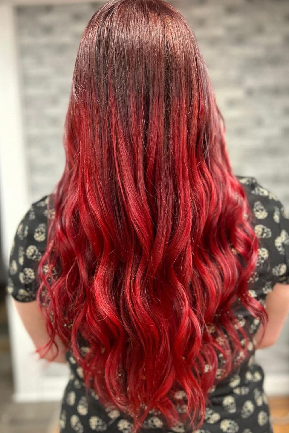 A woman with long wavy sangria red balayage.