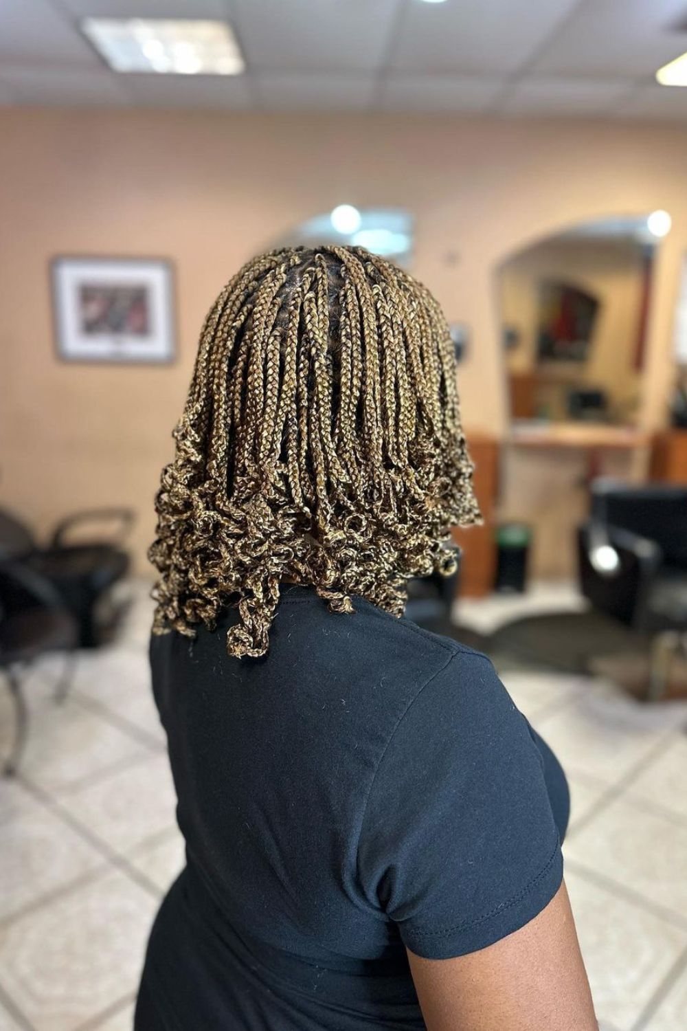 A black woman with shoulder-length blonde box braids with curly ends.
