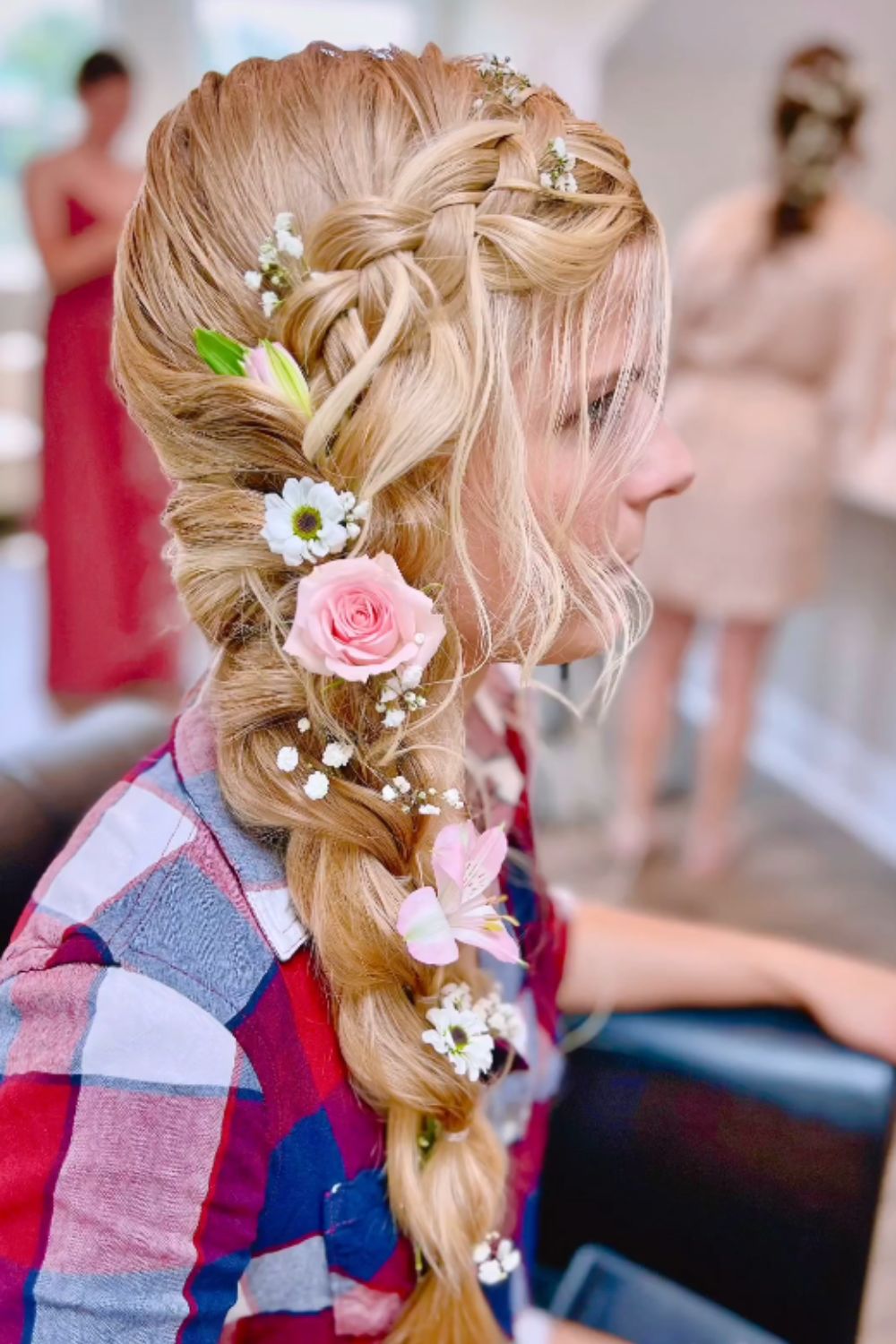 A woman with a blonde side braid with flower accessories.