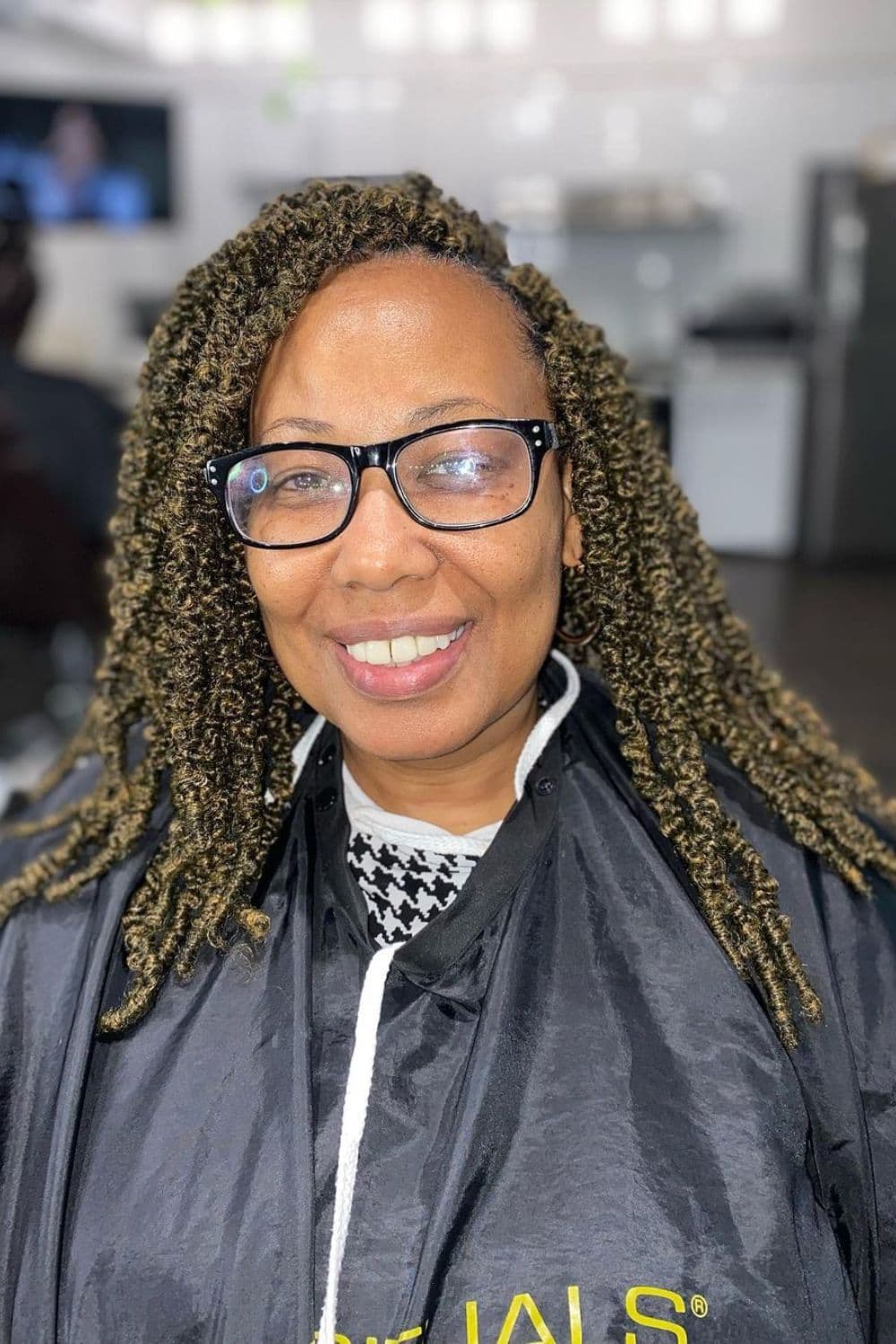 A woman wearing eyeglasses with side-parted crochet braids.