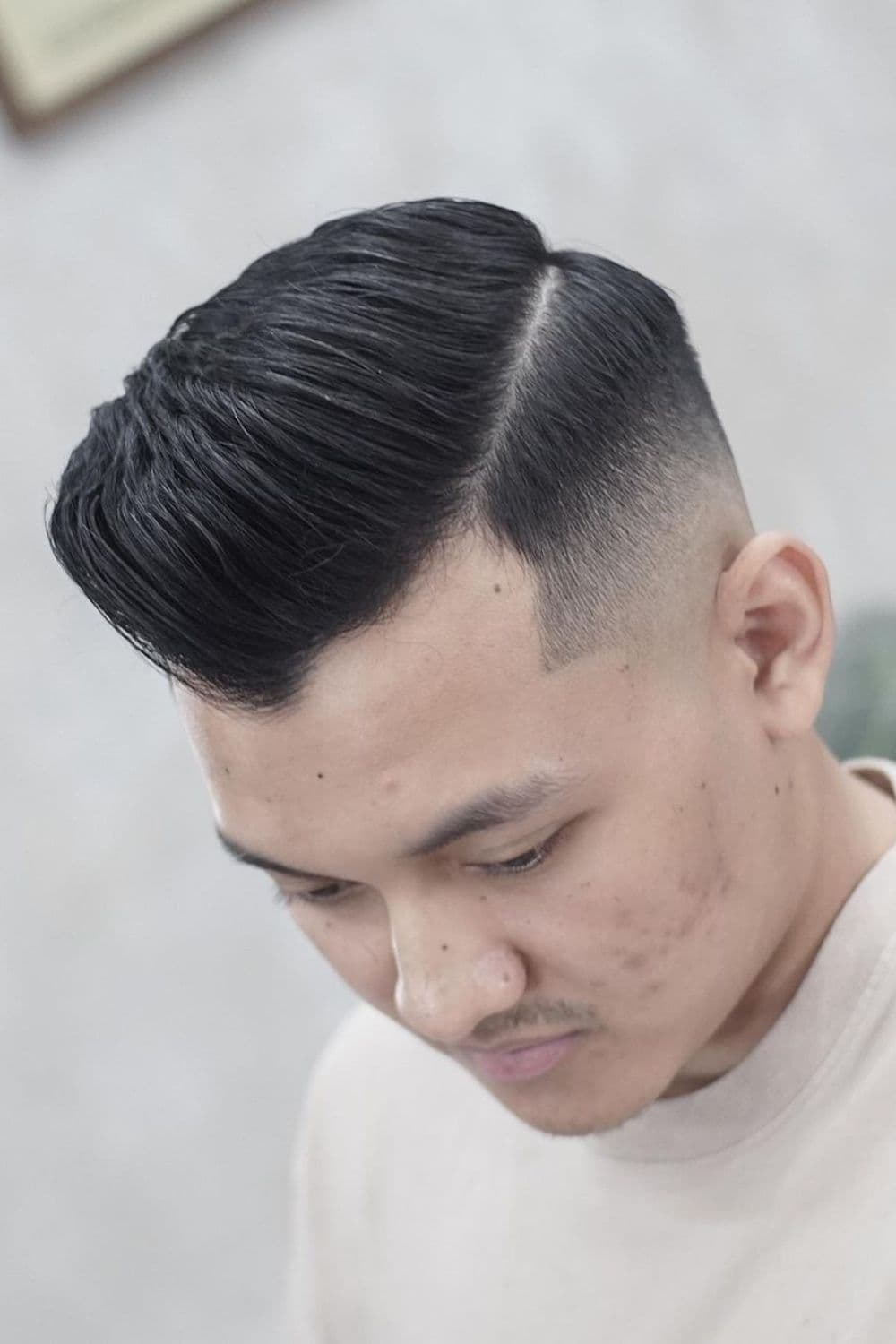 A man with a side-parted fade haircut.